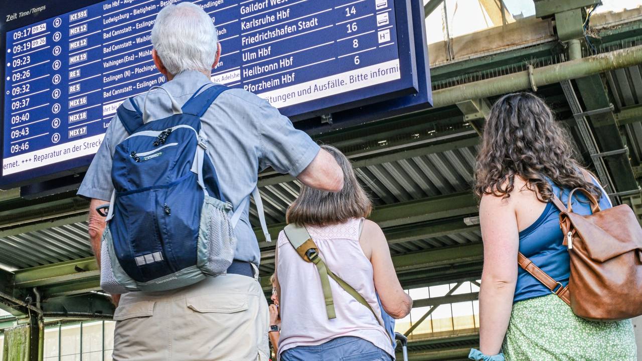 Reisende stehen auf dem Stuttgarter Hauptbahnhof vor einer Anzeigetafel.