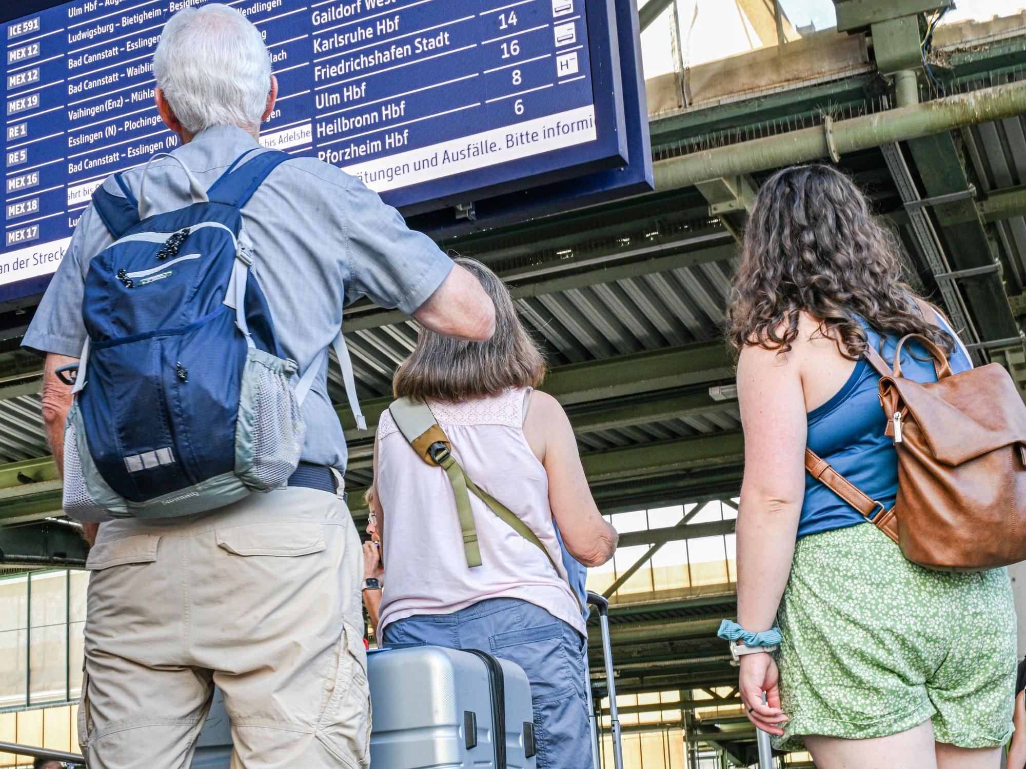 Reisende stehen auf dem Stuttgarter Hauptbahnhof vor einer Anzeigetafel.