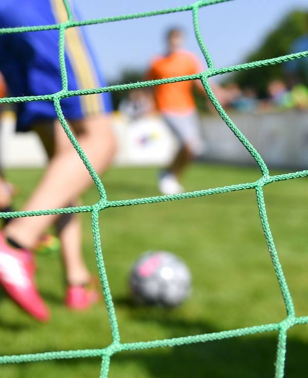 Kinder spielen auf einem Kleinfeld Fußball.