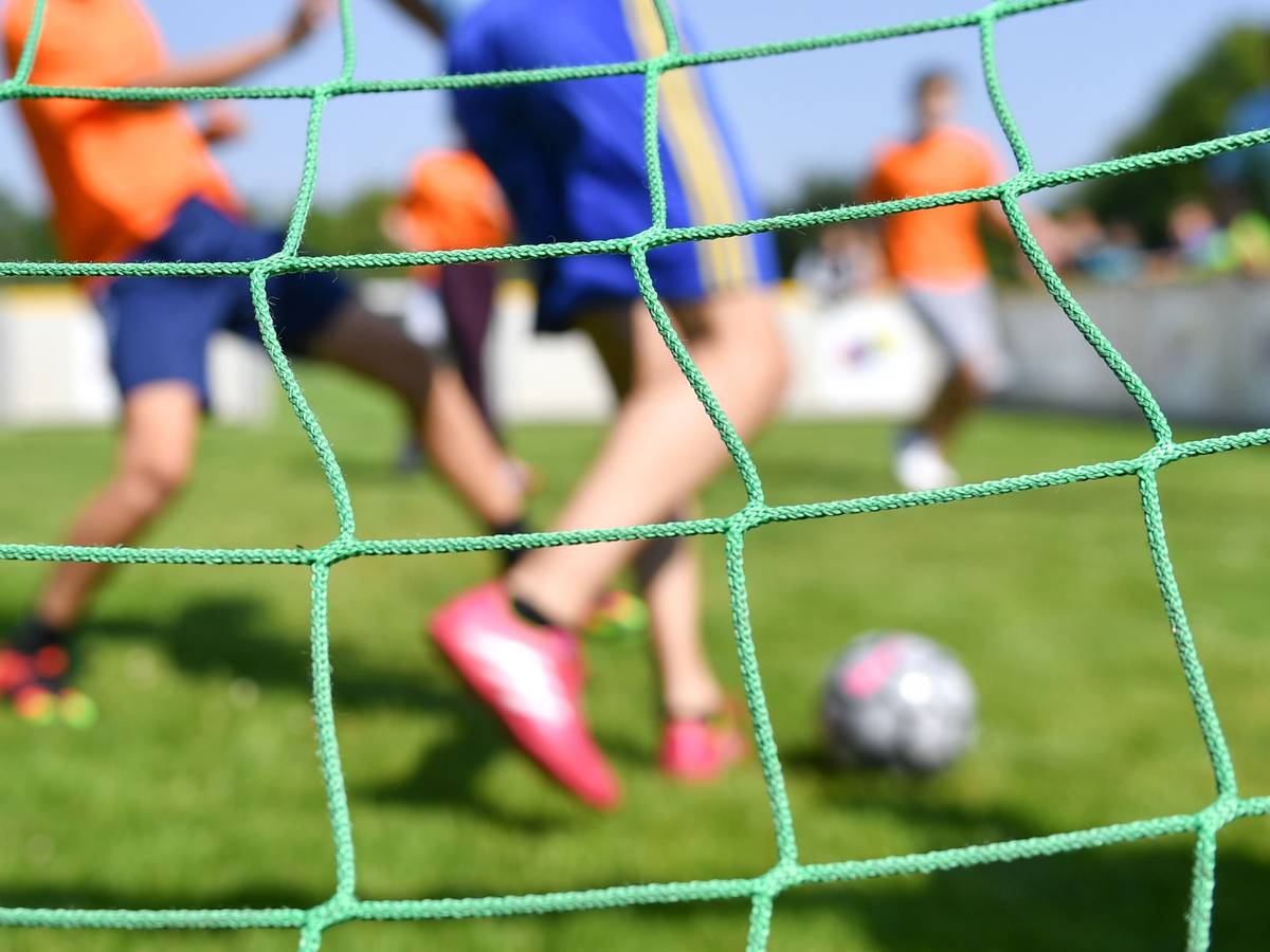 Kinder spielen auf einem Kleinfeld Fußball.