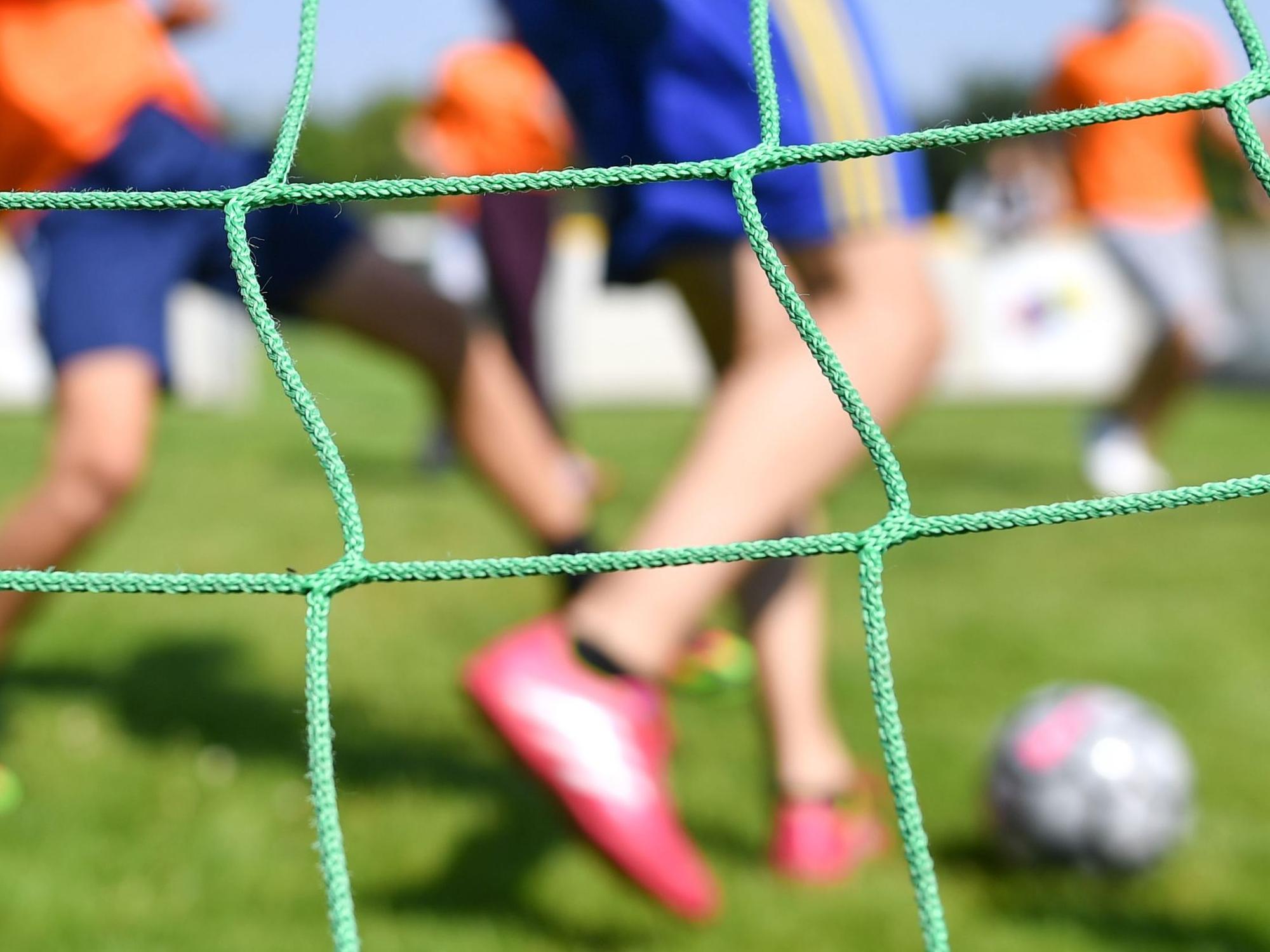 Kinder spielen auf einem Kleinfeld Fußball.