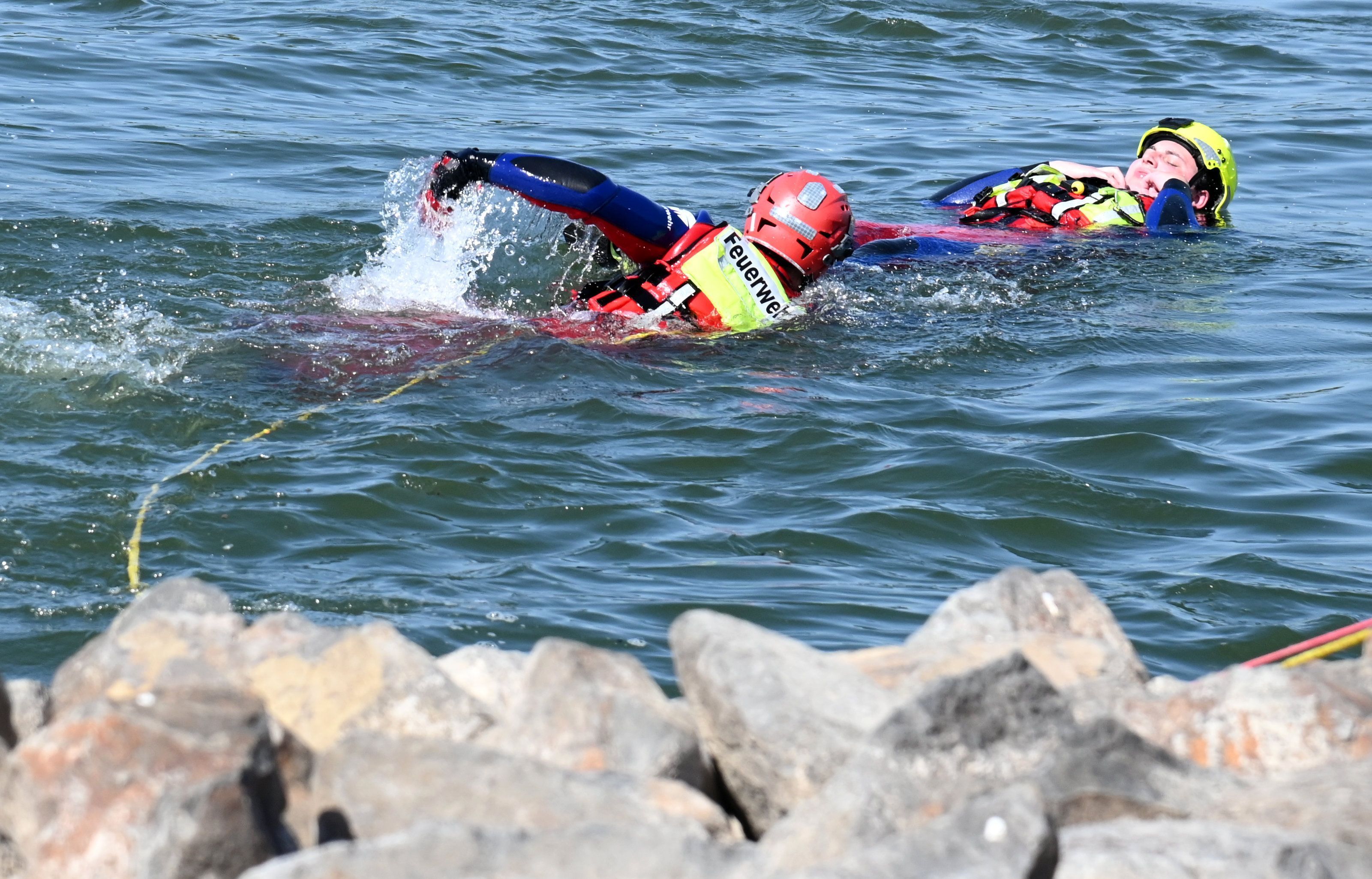 Feuerwehr und DLRG zeigen, wie eine Person aus dem Rhein gerettet wird.