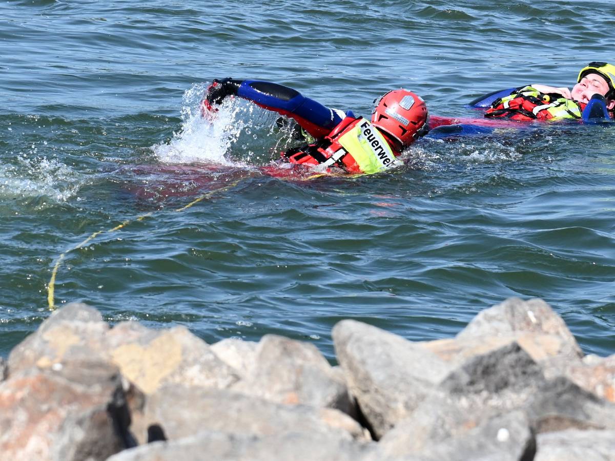 Feuerwehr und DLRG zeigen, wie eine Person aus dem Rhein gerettet wird.
