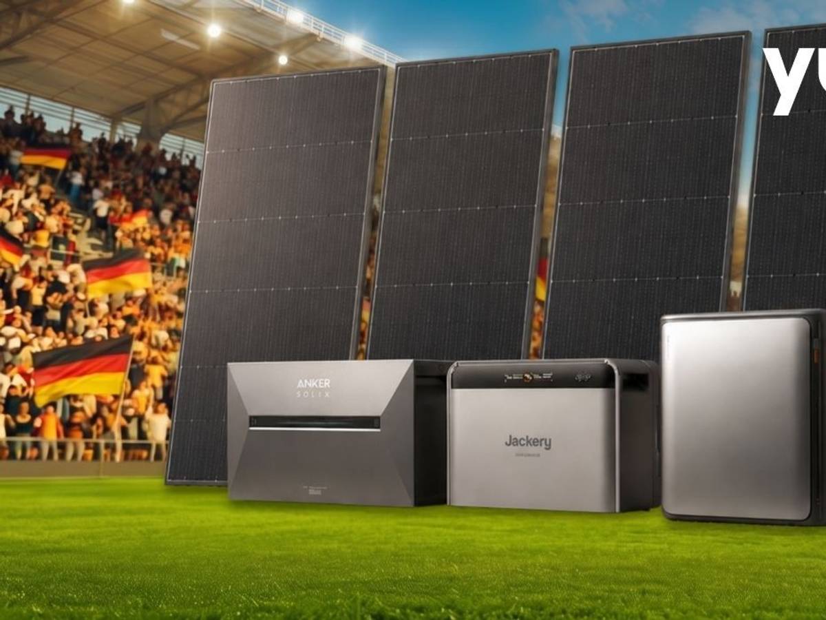 Bild von Yuma: Drei Heimspeicher-Geräte von Anker Solix, EcoFlow und Jackery sowie vier schwarze Solarmodule vor einem vollbesetzten Fußballstadion mit Zuschauern und vielen Deutschland-Fahnen im Hintergrund.