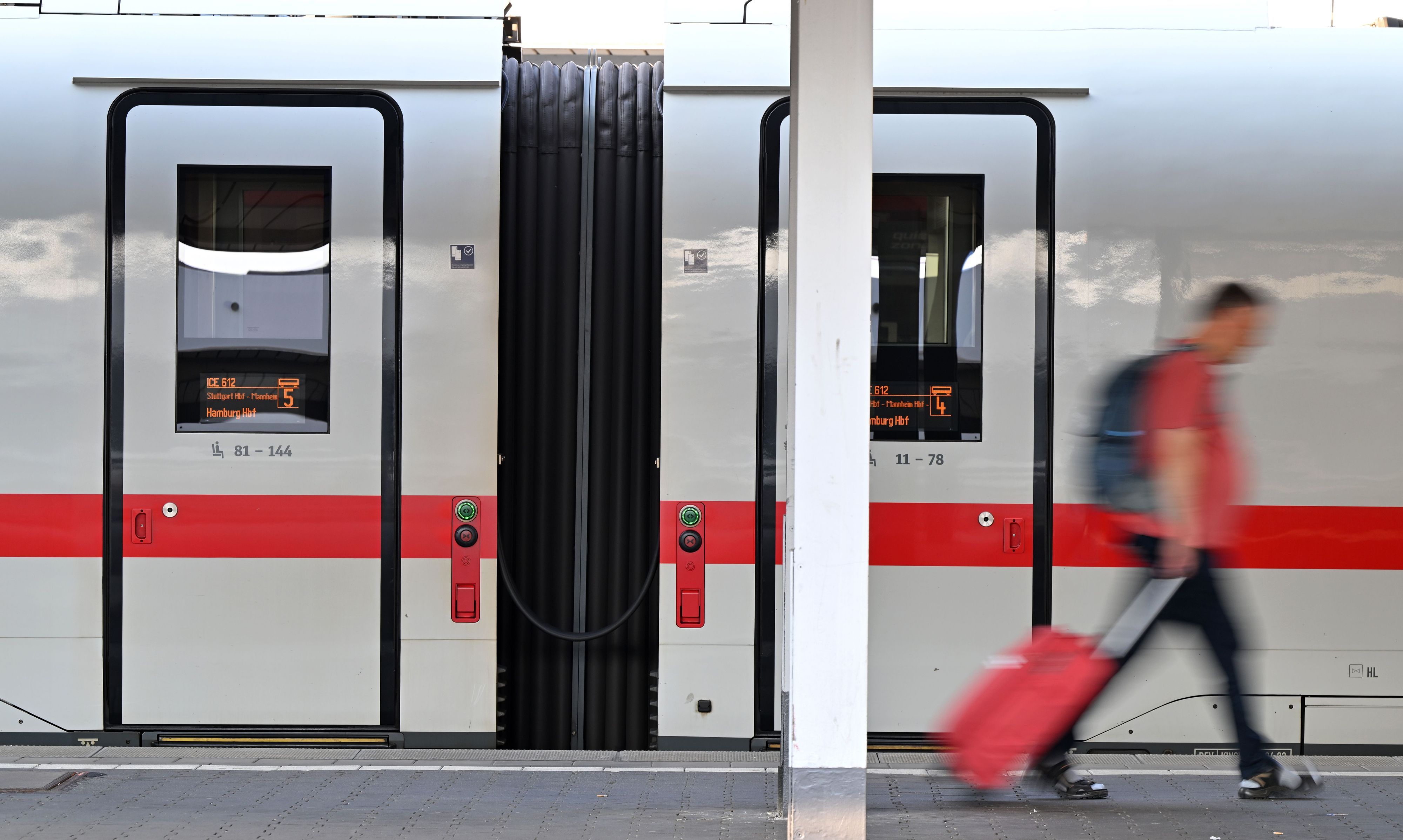 Ein Passagier läuft am Hauptbahnhof München an einem ICE-Zug vorbei. Die Deutsche Bahn rät aktuell vom Reisen ab.