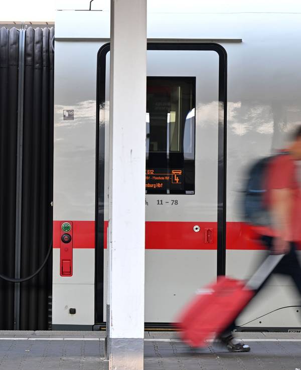 Ein Passagier läuft am Hauptbahnhof München an einem ICE-Zug vorbei. Die Deutsche Bahn rät aktuell vom Reisen ab.