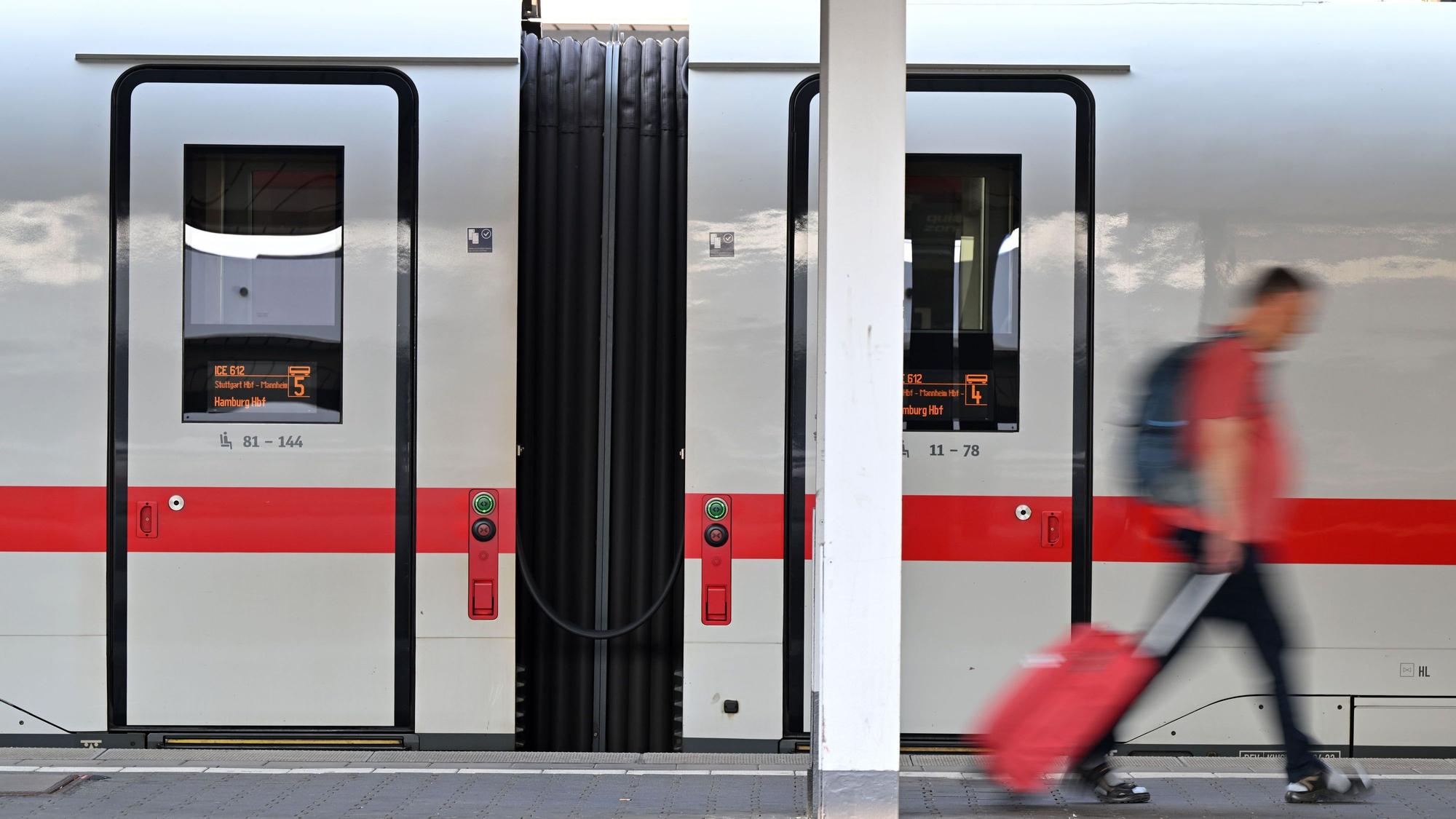 Ein Passagier läuft am Hauptbahnhof München an einem ICE-Zug vorbei. Die Deutsche Bahn rät aktuell vom Reisen ab.