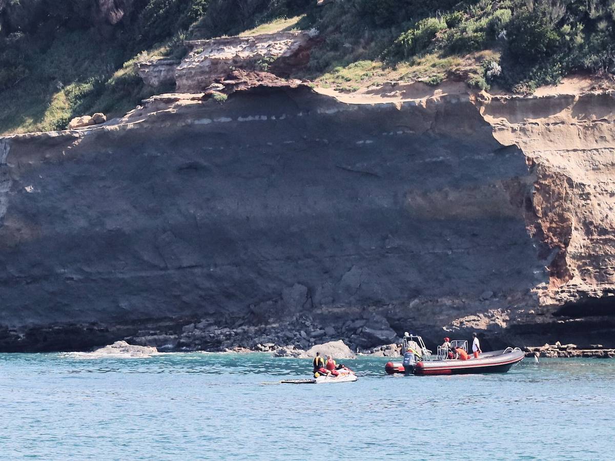 Rettungskräfte suchen von Booten aus nach einer vermissten Person in der Nähe eines riesigen Küstenabschnitts. Am Mittwochabend ist ein großer Felsen von einer Steilküste abgebrochen und ins Meer gestürzt, wobei ein Taucher ums Leben kam und ein weiterer vermisst wird.