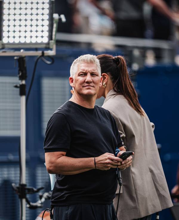 ARD-Experte Bastian Schweinsteiger mit Handy am Spielfeldrand.