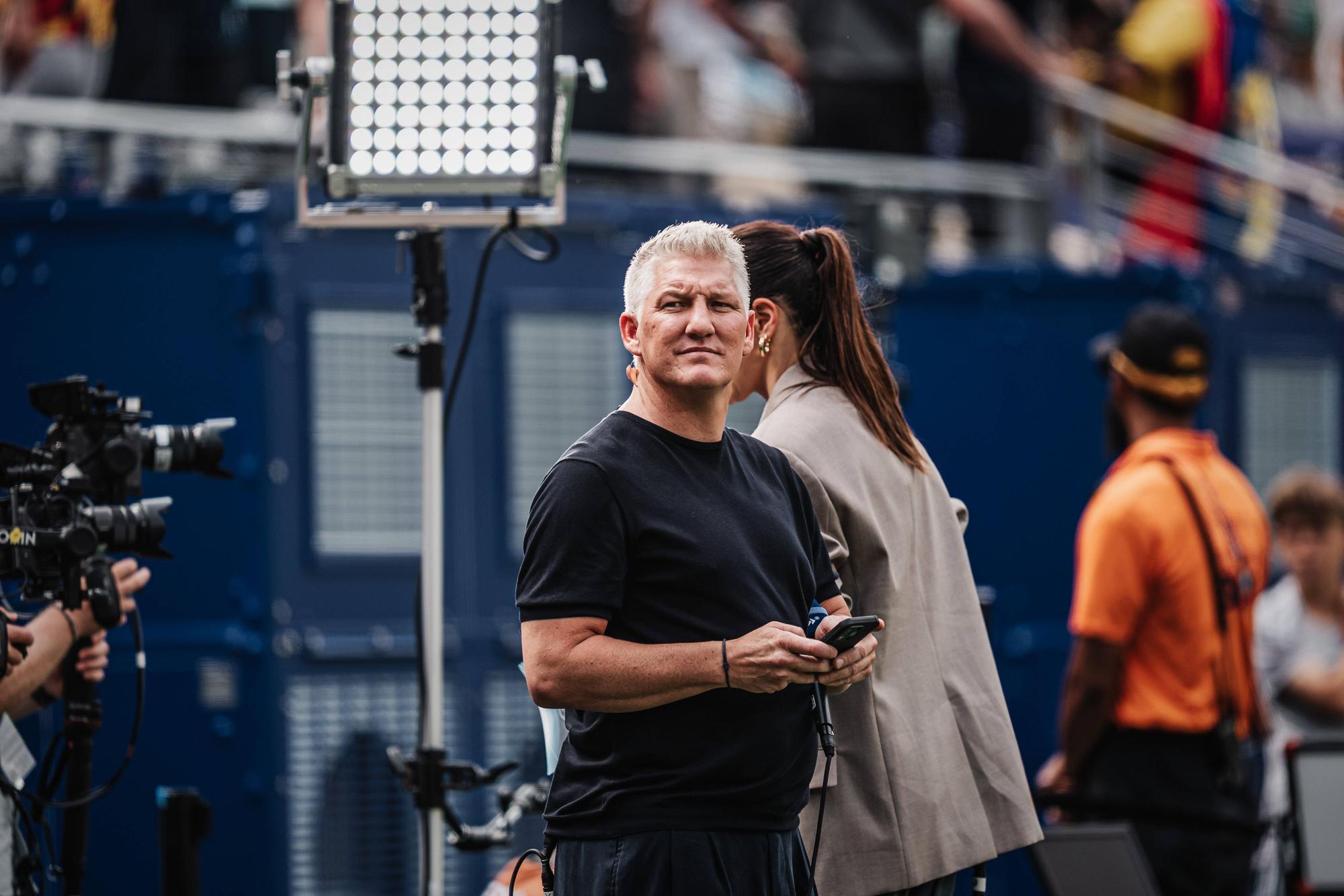 ARD-Experte Bastian Schweinsteiger mit Handy am Spielfeldrand.