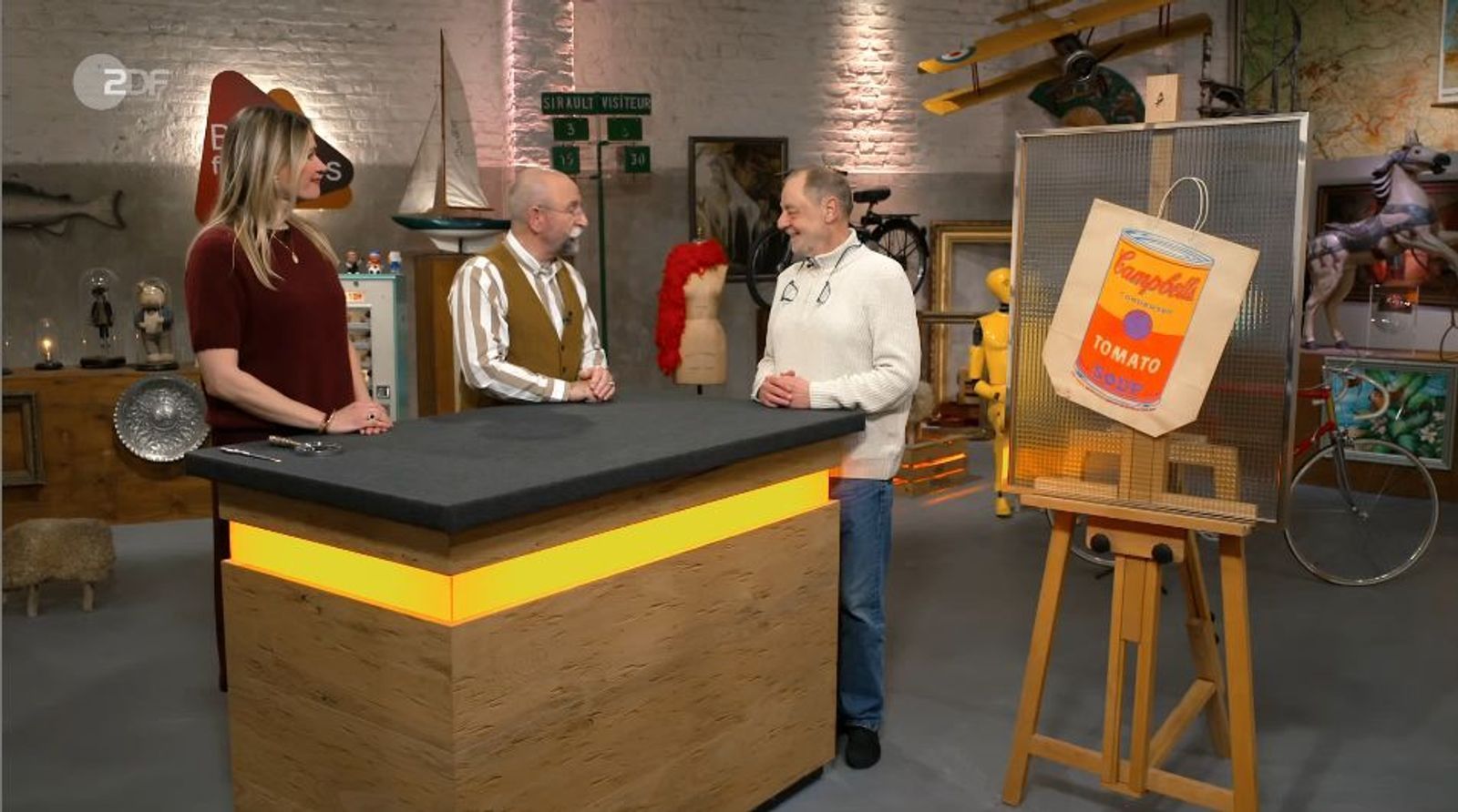 Verkäufer Franz-Josef (rechts) bringt einen Farbsiebdruck auf einer Papiertüte mit. Der Druck stammt aus dem Jahr 1966 und ist von Andy Warhol. Franz-Joseph ist mit dem Ergebnis zufrieden: Er kann er das Stück für 1.650 Euro an den Kunsthändler Julian Schmitz-Avila verkaufen. (Bild: ZDF)