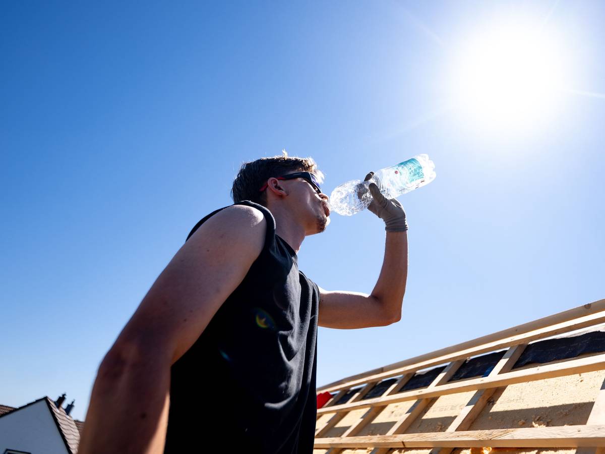 Ein Dachdecker trinkt Wasser unter der sengenden Sonne bei über 30 Grad auf dem Dach eines Hauses im Rhein-Sieg-Kreis.