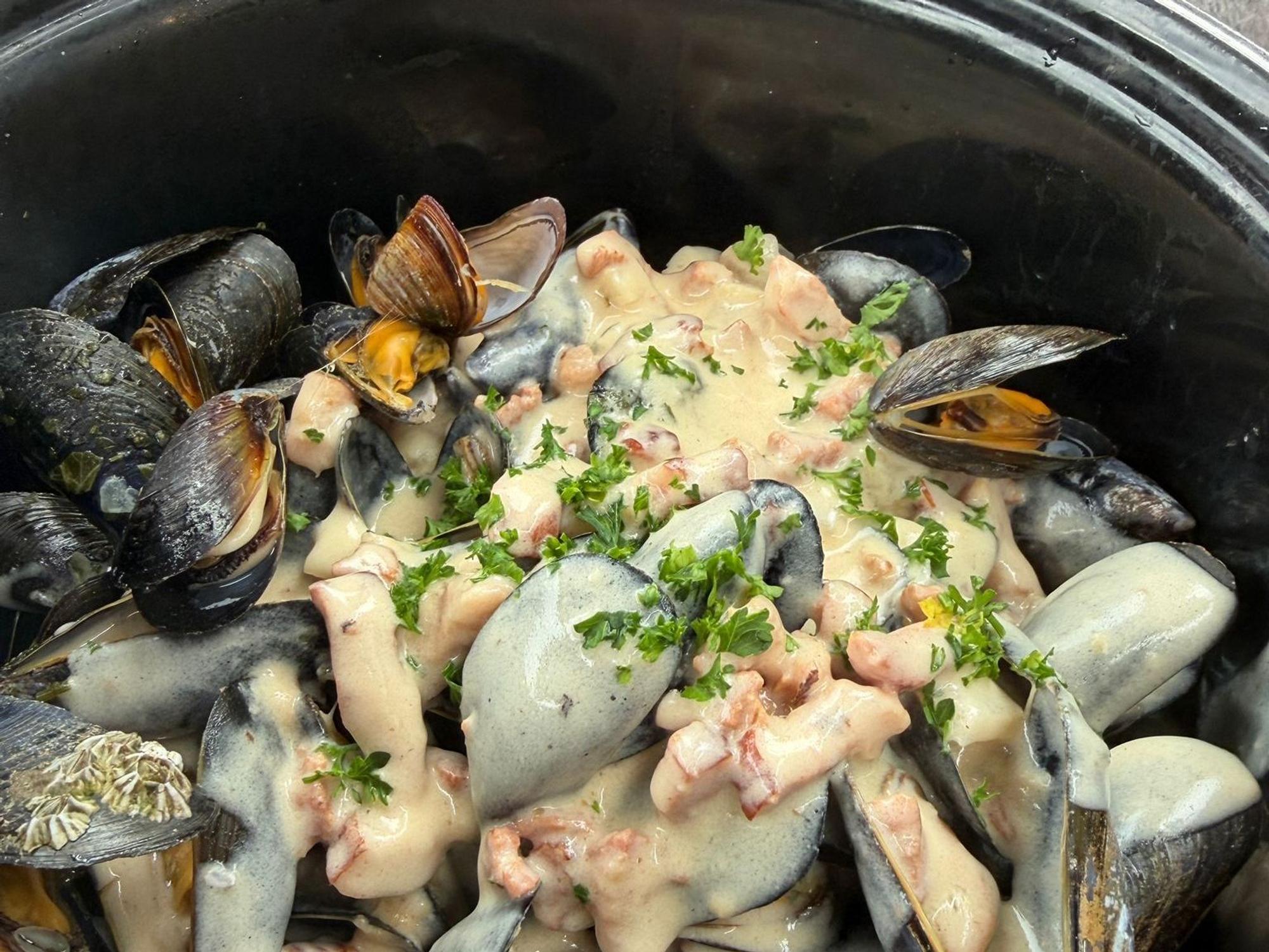 Ein Topf mit gekochten Miesmuschelnmund einer cremigen Sauce