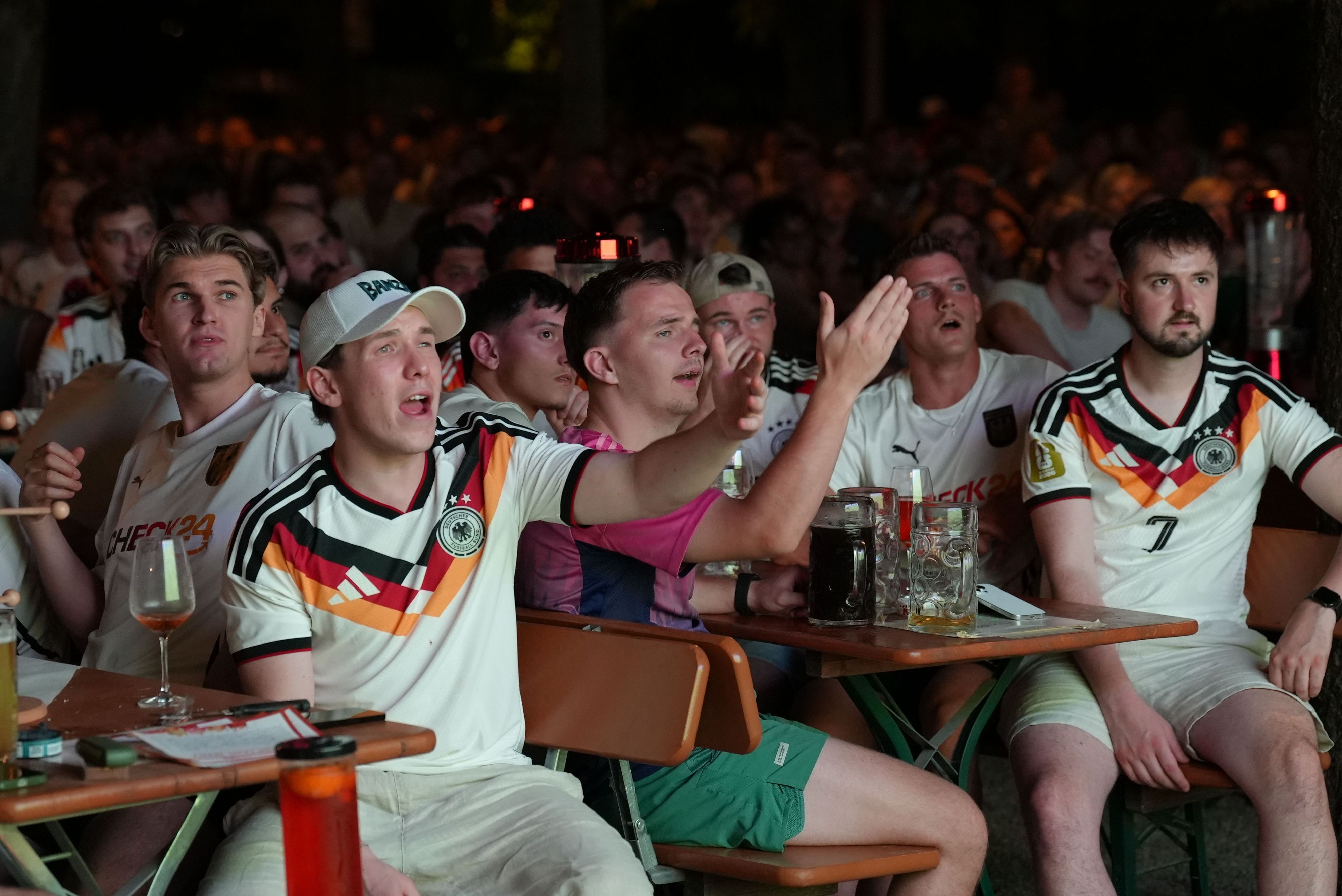 Fans verfolgen das Spiel beim Public Viewing und reagieren enttäuscht auf eine Spielszene.