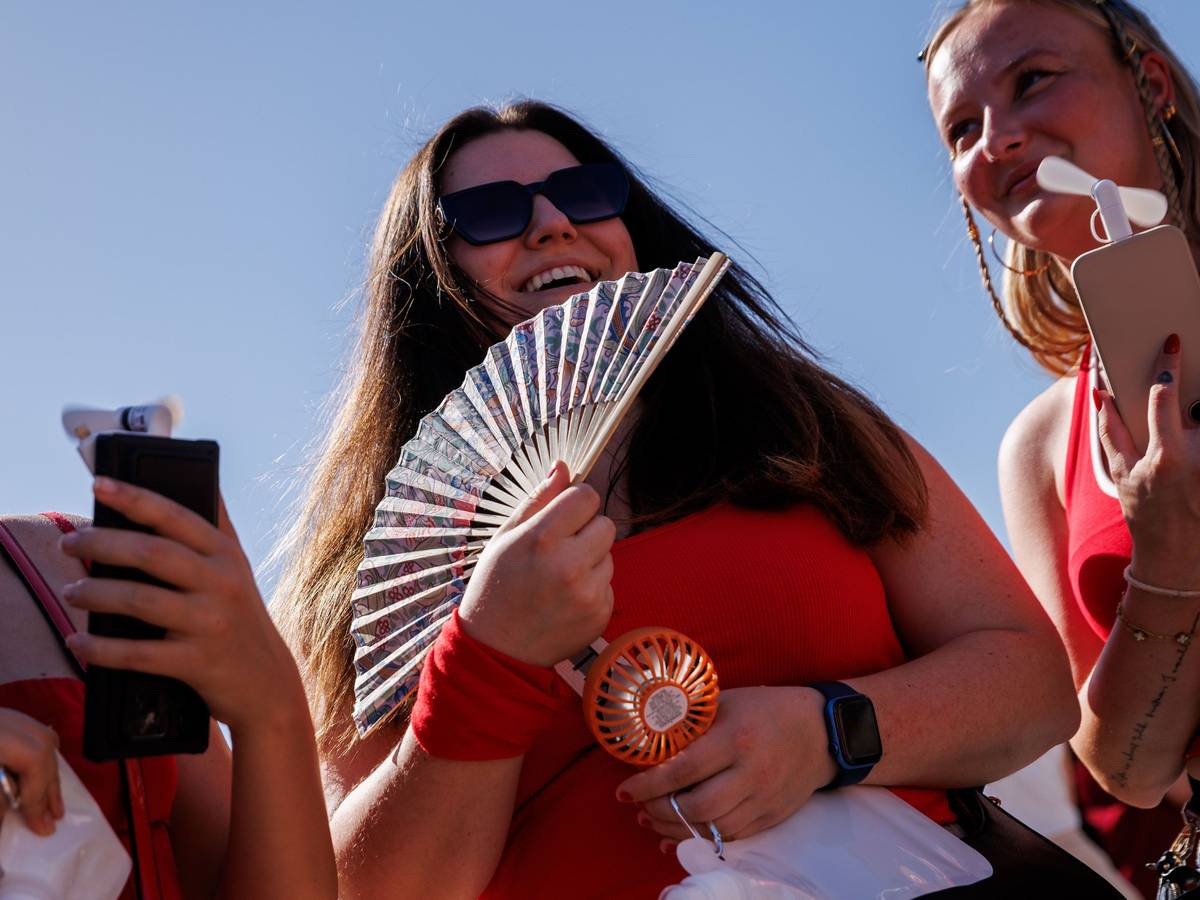 Zwei junge Frauen halten auf dem Weg zum Konzert des US-amerikanischen Musikers Bruno Mars im Olympiastadion zur Kühlung einen Fächer und einen Taschenventilator in der Hand.