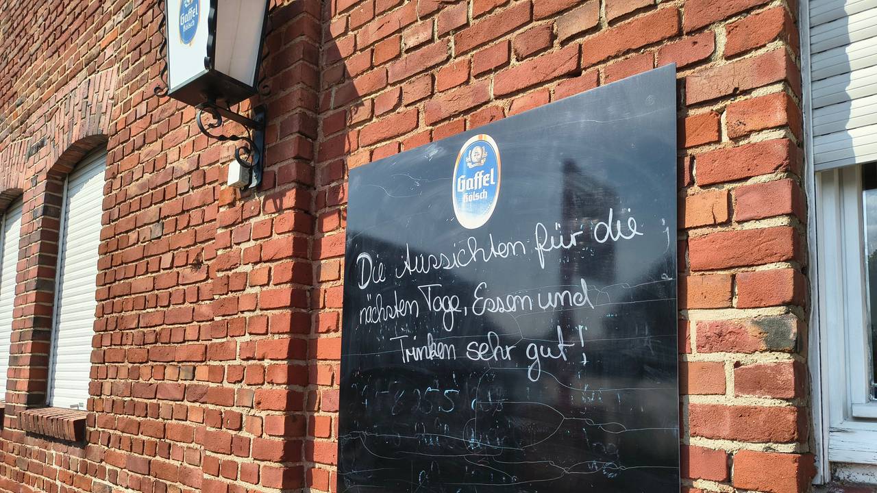 Auf einer Tafel an der Gaststätte in Köln-Merkenich in Langel werden Besucher noch herzlich empfangen. Bald schließt die Gastro in Rheinnähe.