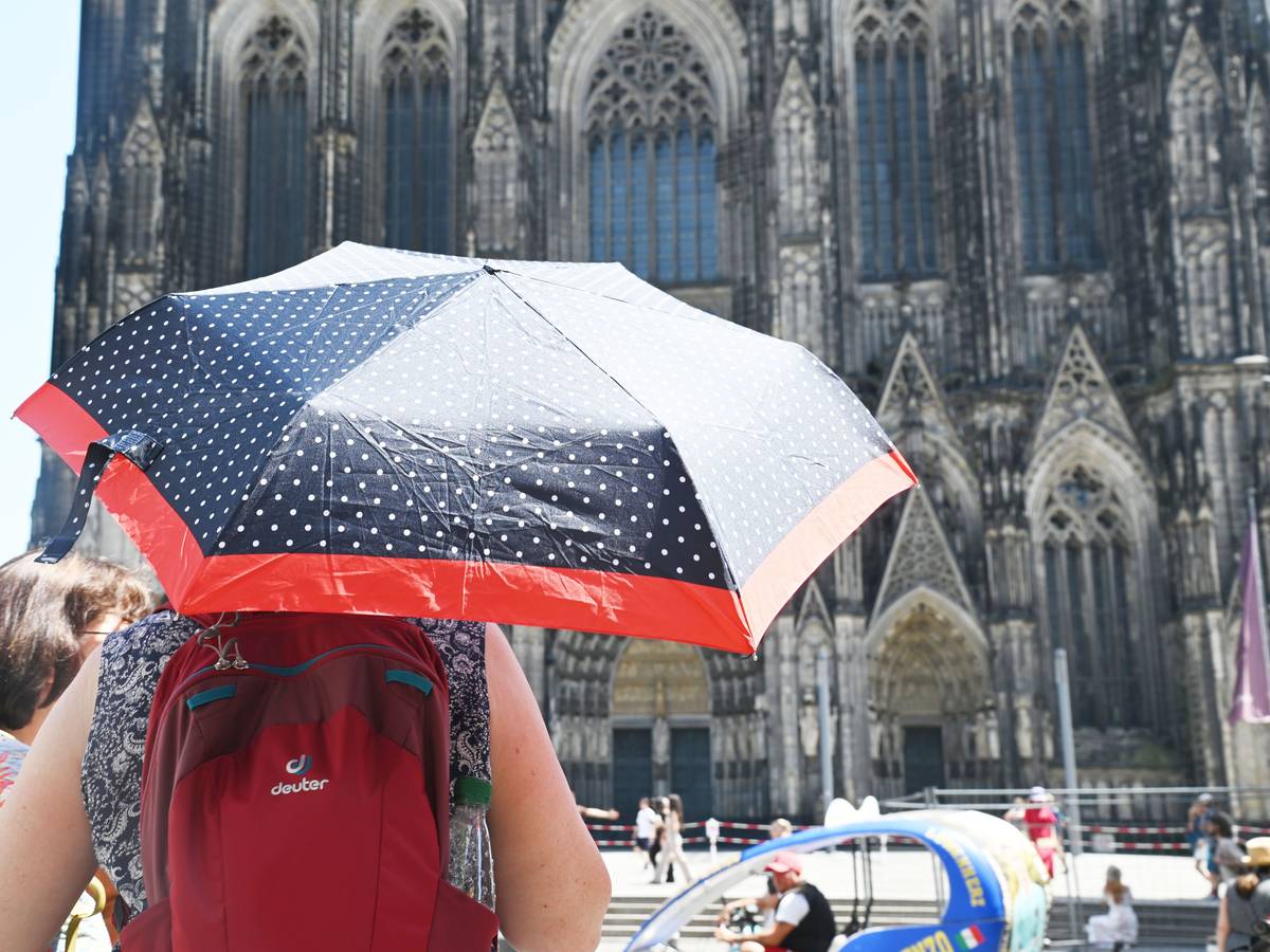 Eine Person schützt sich mit einem Schirm vor der Sonne.