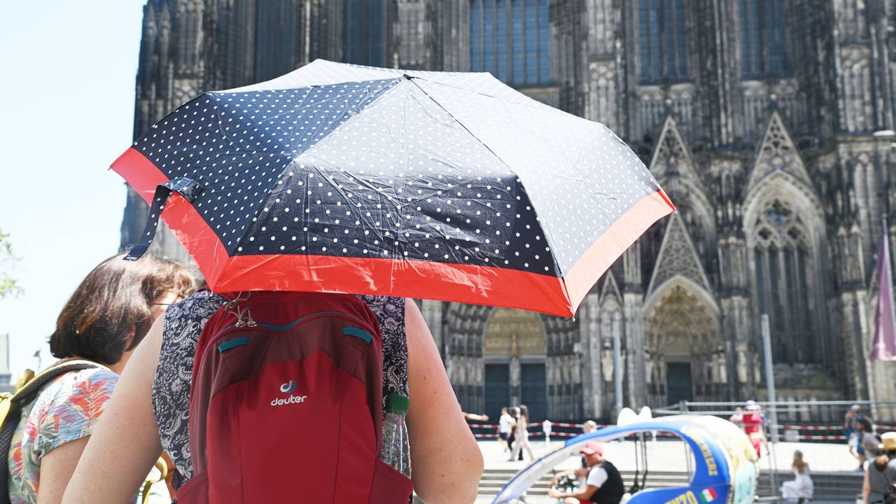 Eine Person schützt sich mit einem Schirm vor der Sonne.