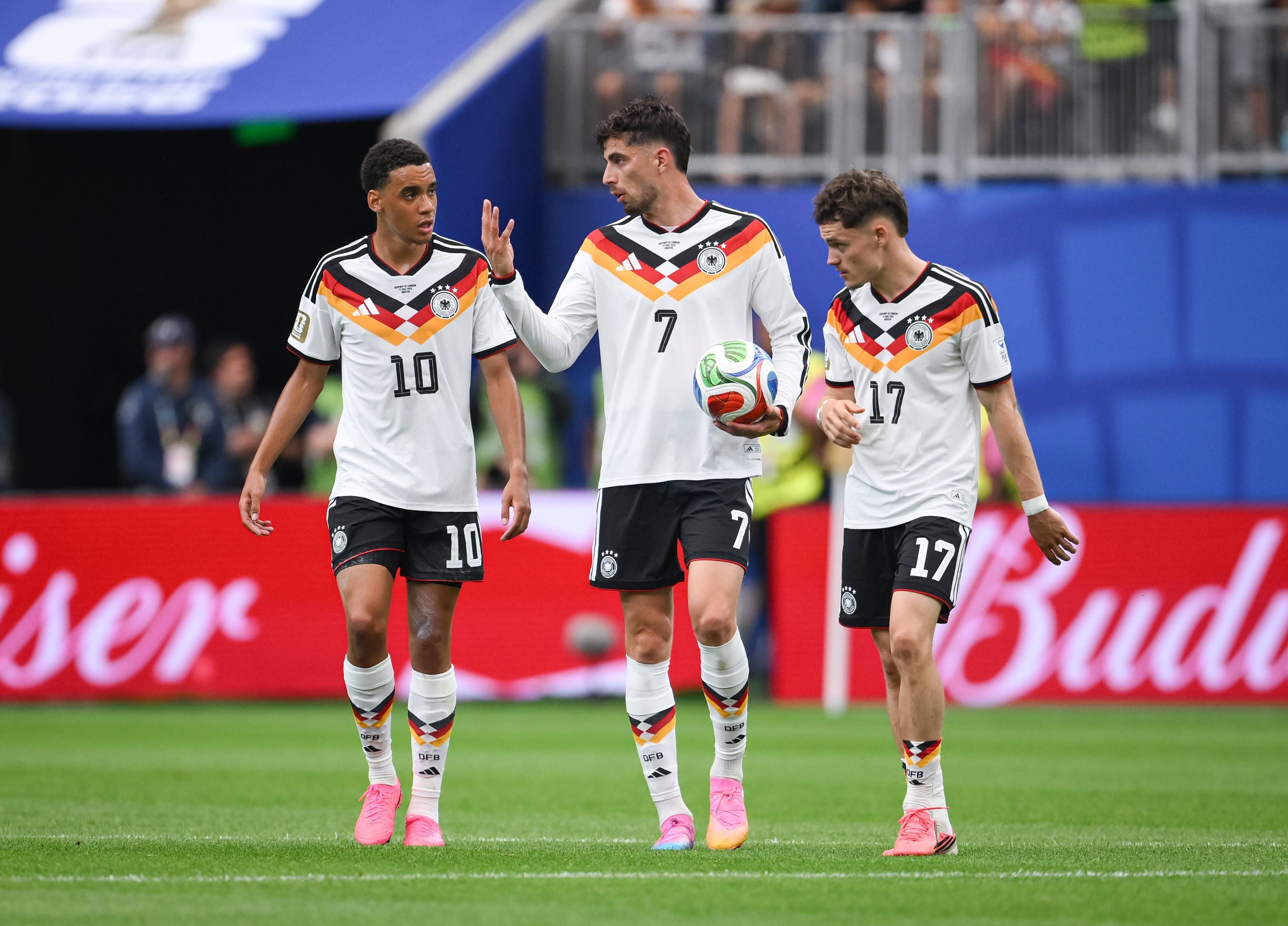 Jamal Musiala, Kai Havertz und Florian Wirtz diskutieren nachdenklich im DFB-Trikot.