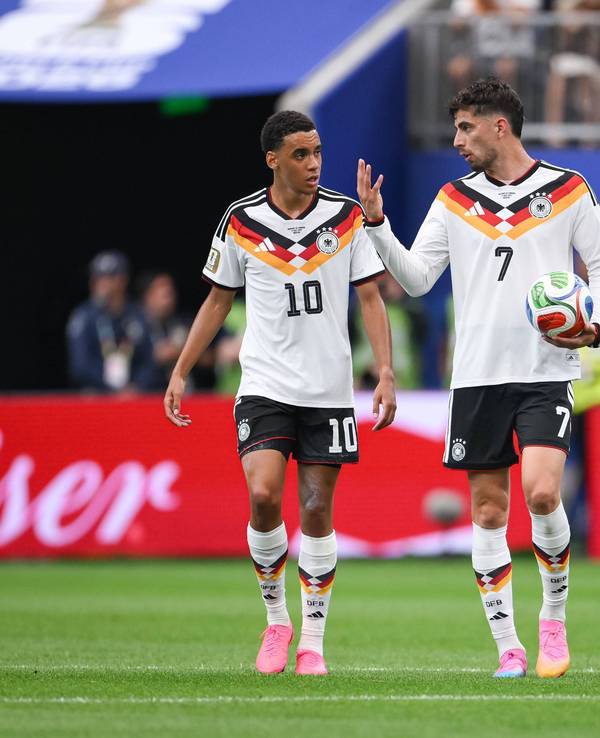 Jamal Musiala, Kai Havertz und Florian Wirtz diskutieren nachdenklich im DFB-Trikot.