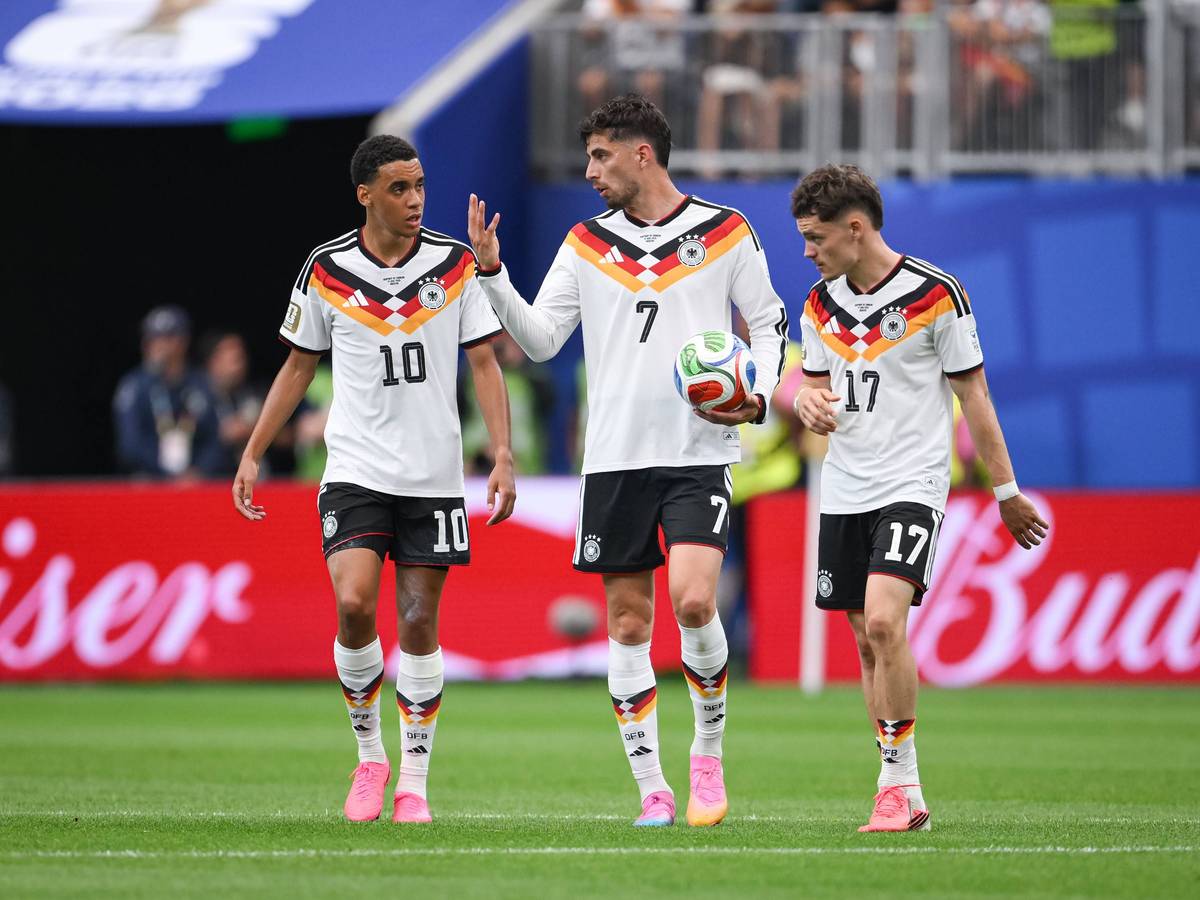 Jamal Musiala, Kai Havertz und Florian Wirtz diskutieren nachdenklich im DFB-Trikot.