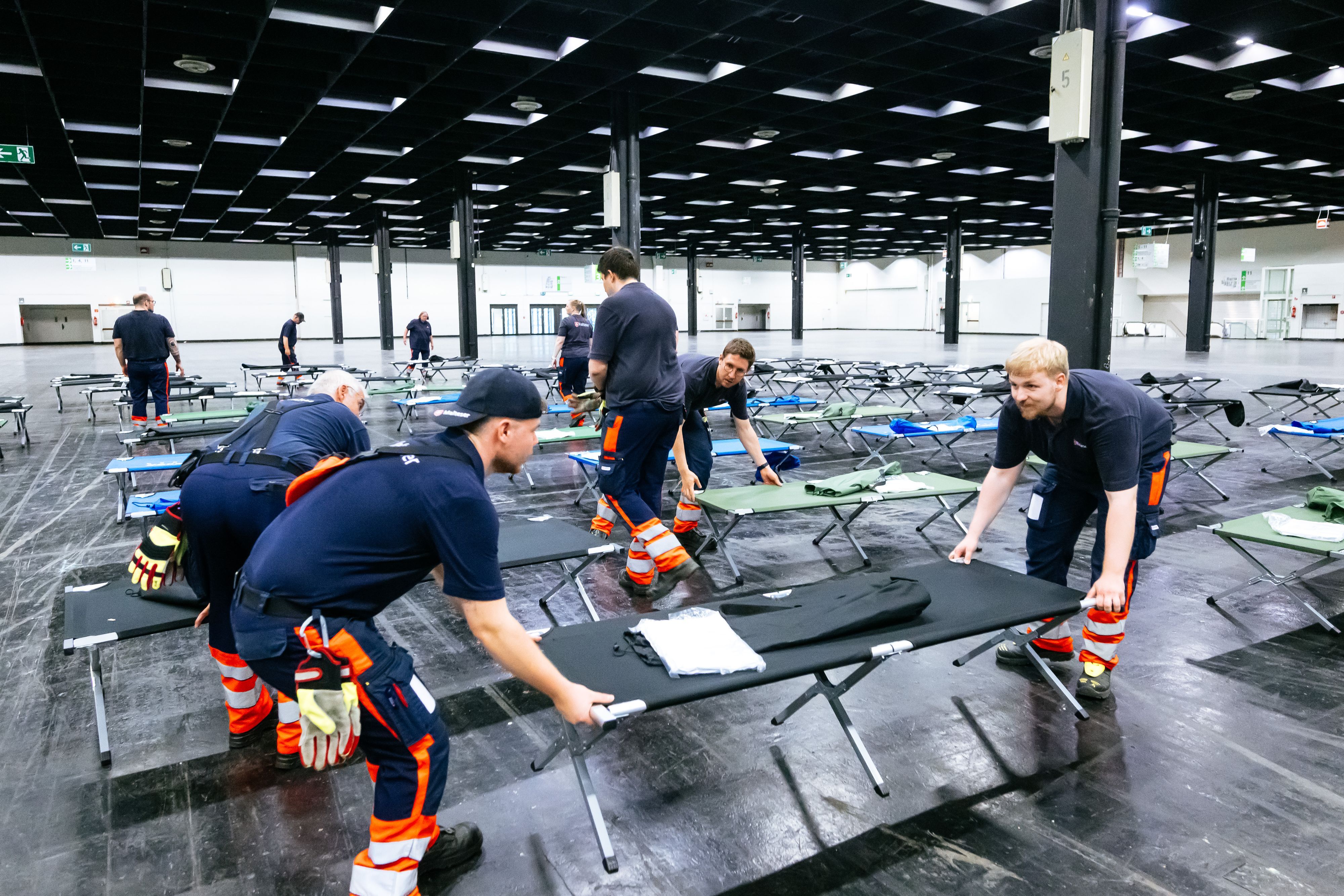 Helfer bauen das Notfallversorgungszentrum in einer Messehalle auf.