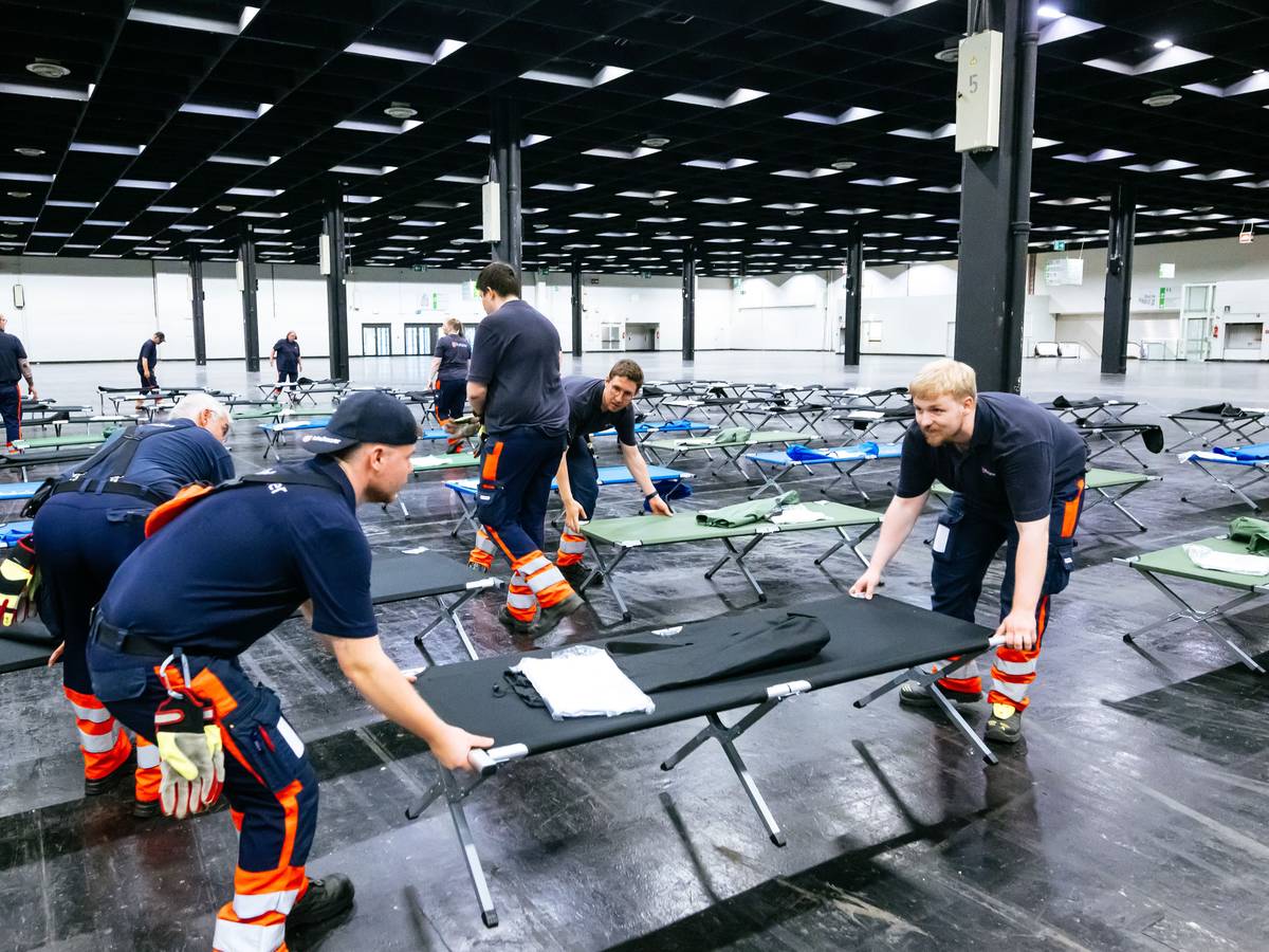Helfer bauen das Notfallversorgungszentrum in einer Messehalle auf.