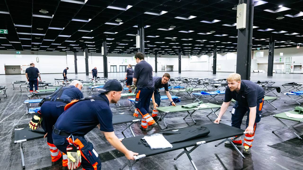 Helfer bauen das Notfallversorgungszentrum in einer Messehalle auf.