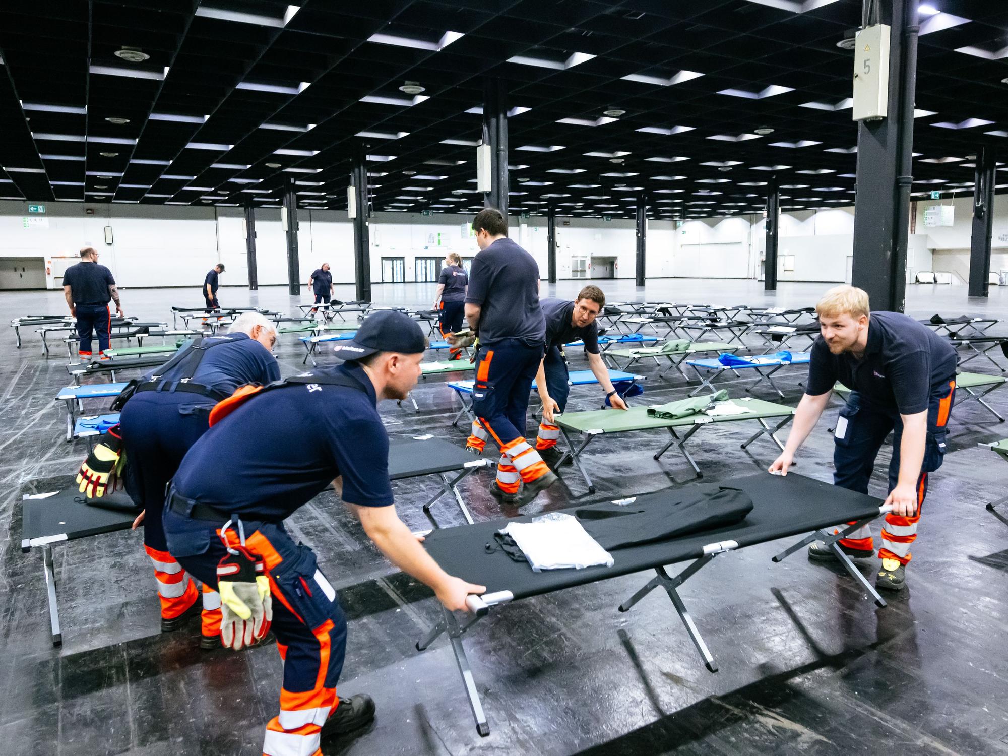 Helfer bauen das Notfallversorgungszentrum in einer Messehalle auf.