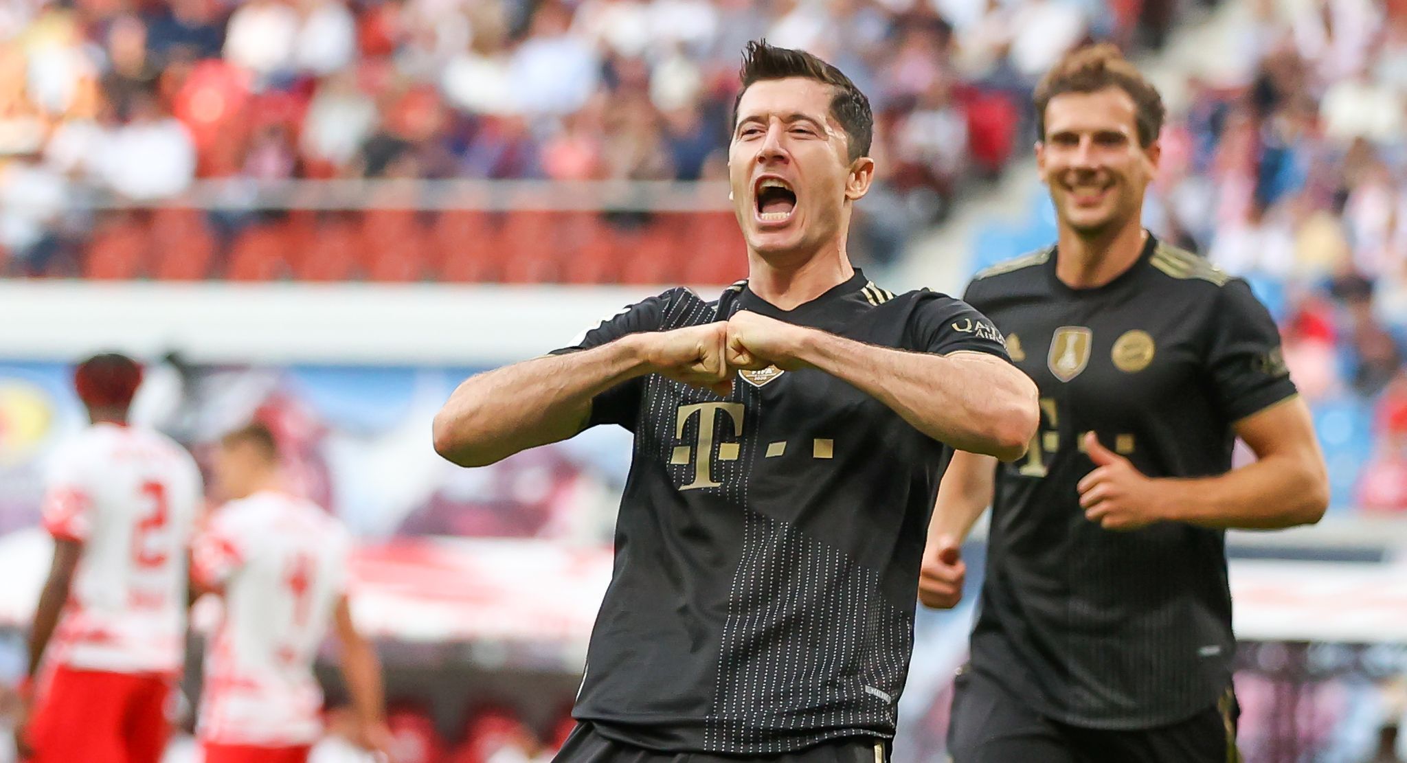 Robert Lewandowski jubelt im Bayern-Trikot, im HIntergrund grinst Leon Goretzka.