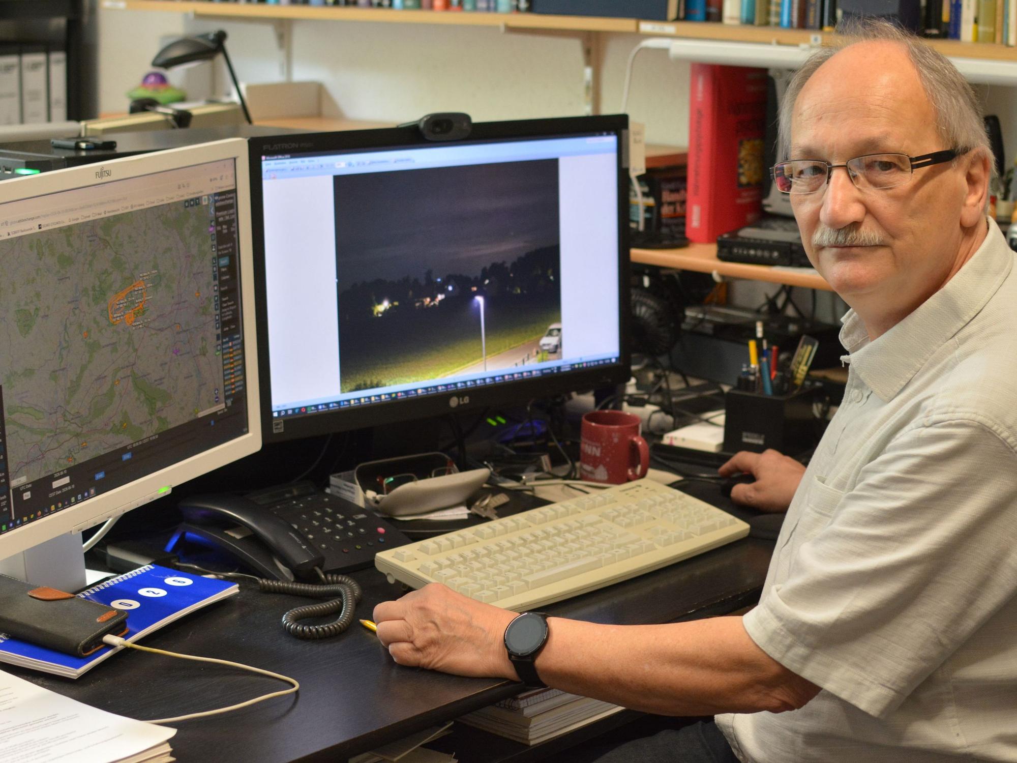 UFO-Forscher Hans-Werner Peiniger sitzt vor zwei Computermonitoren an einem Schreibtisch und wertet Aufnahmen aus.