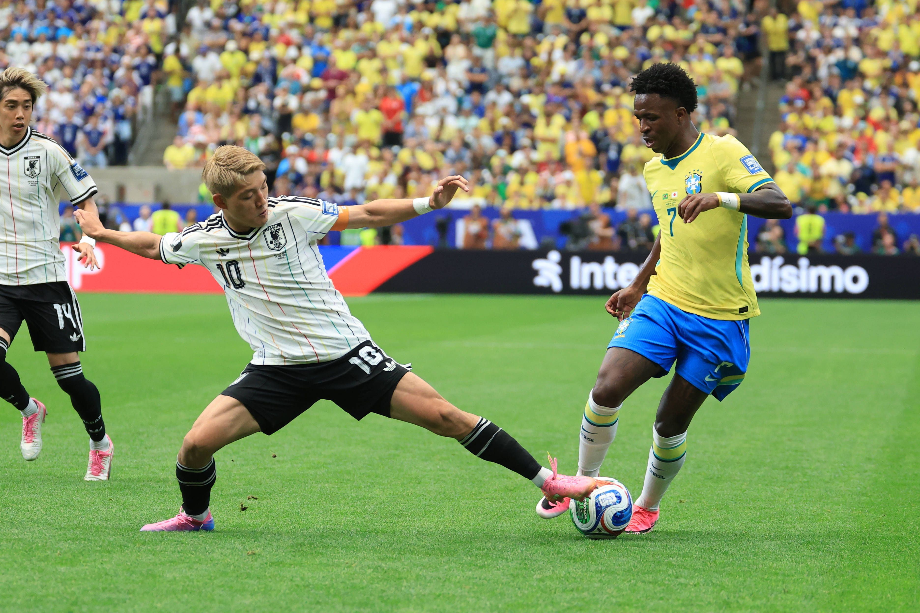 Ritsu Doan versucht, Vini Jr. den Ball vom Fuß zu spitzeln.