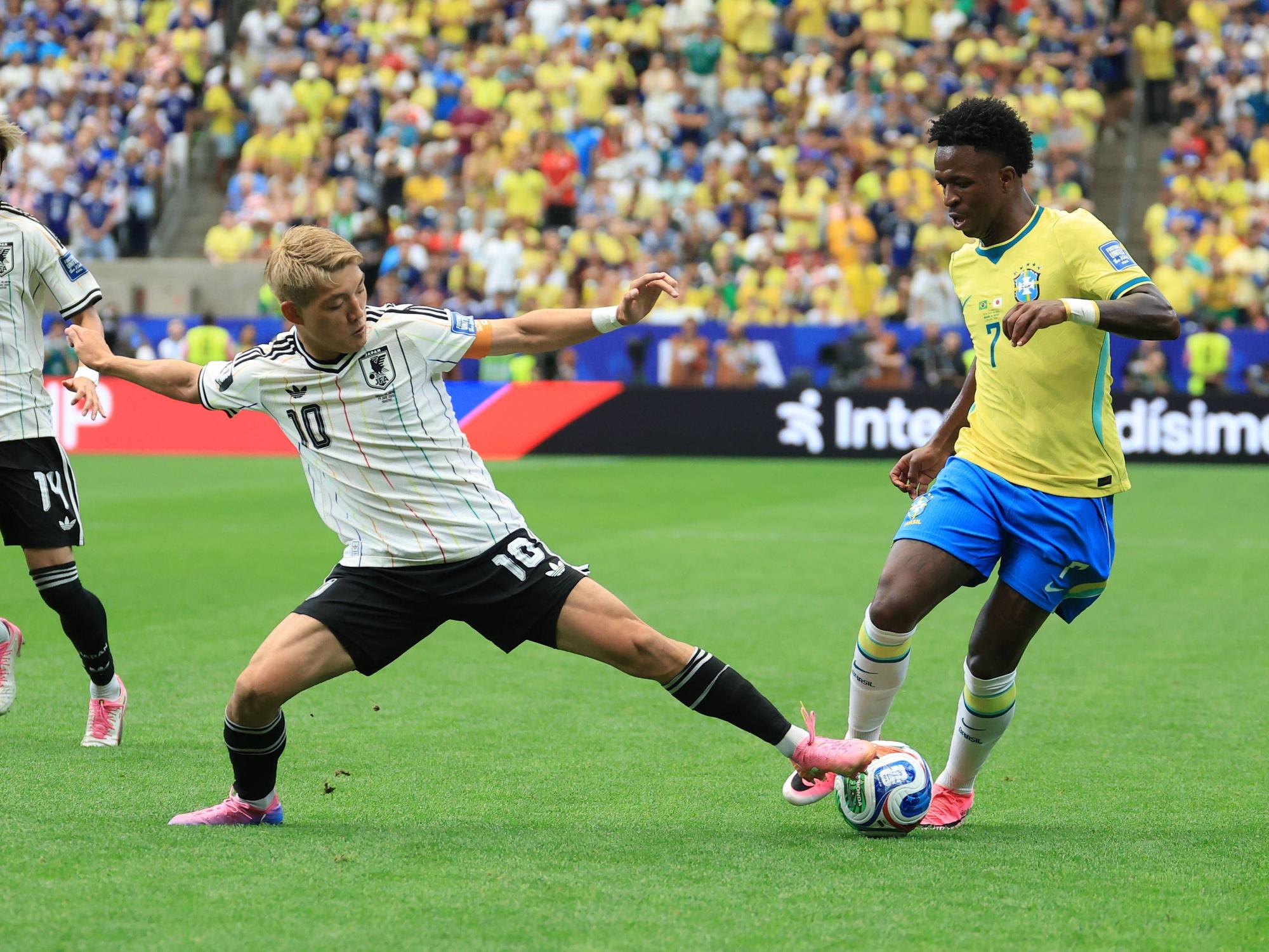 Ritsu Doan versucht, Vini Jr. den Ball vom Fuß zu spitzeln.
