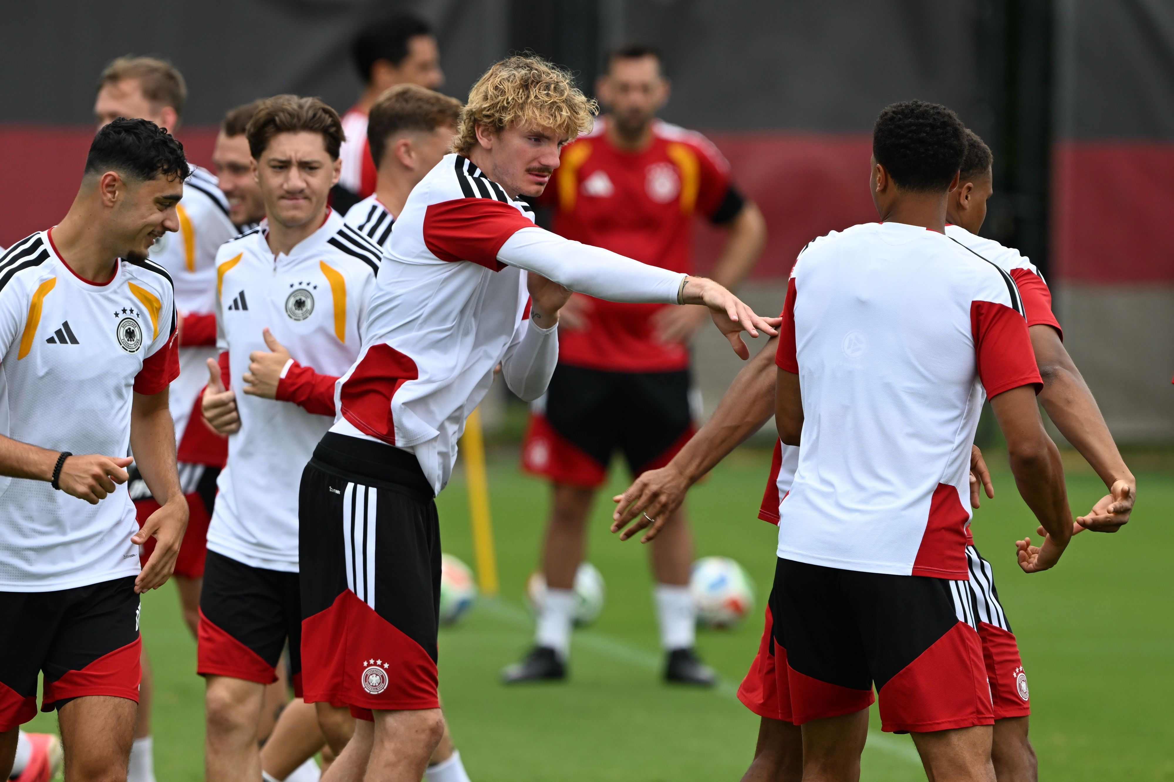 Nick Woltemade (M,l) tippt seinen Mitspieler während des Trainings an.