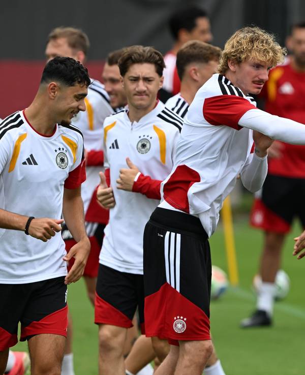 Nick Woltemade (M,l) tippt seinen Mitspieler während des Trainings an.