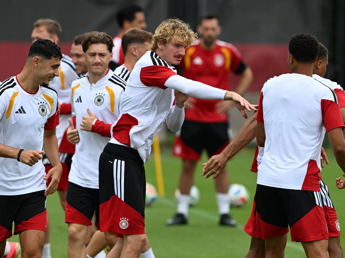 Nick Woltemade (M,l) tippt seinen Mitspieler während des Trainings an.
