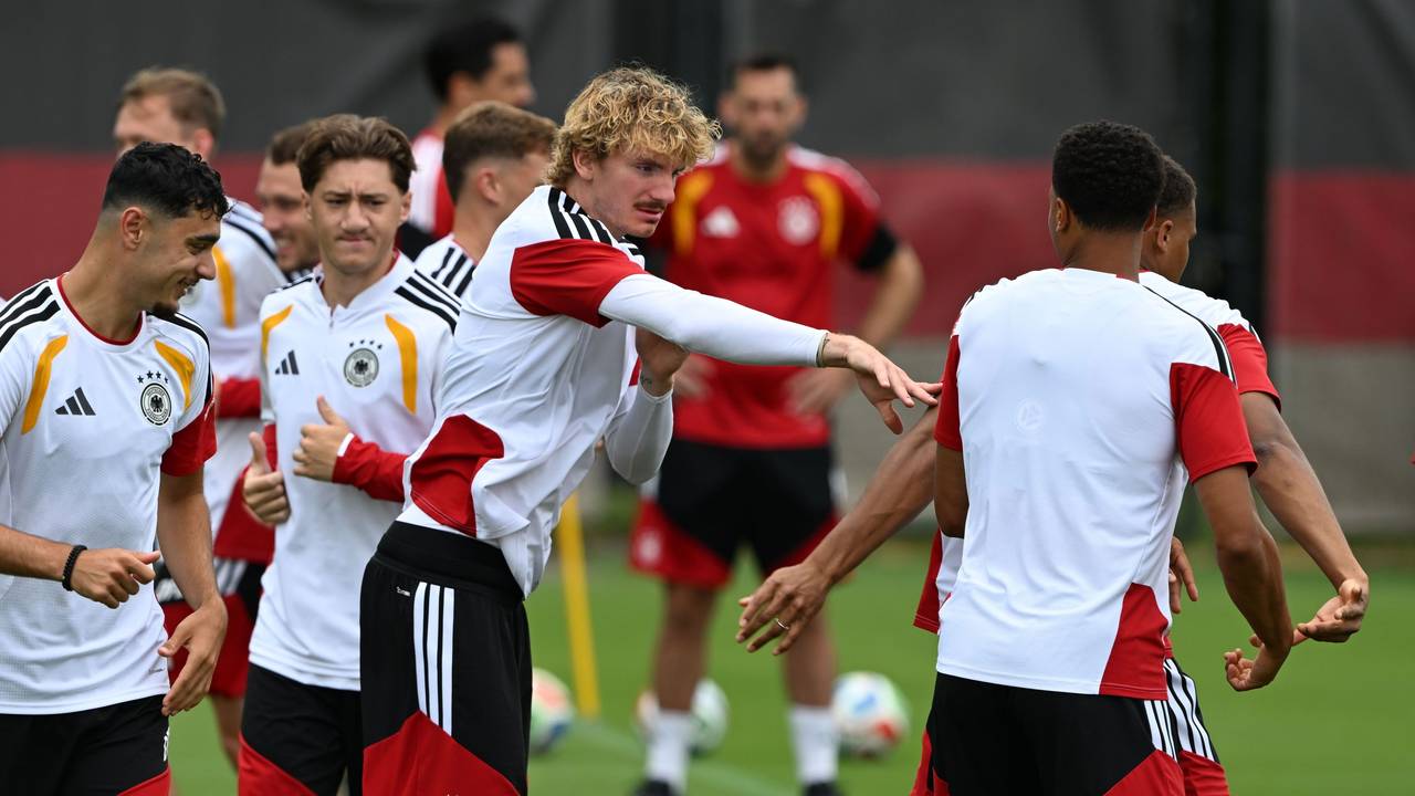 Nick Woltemade (M,l) tippt seinen Mitspieler während des Trainings an.