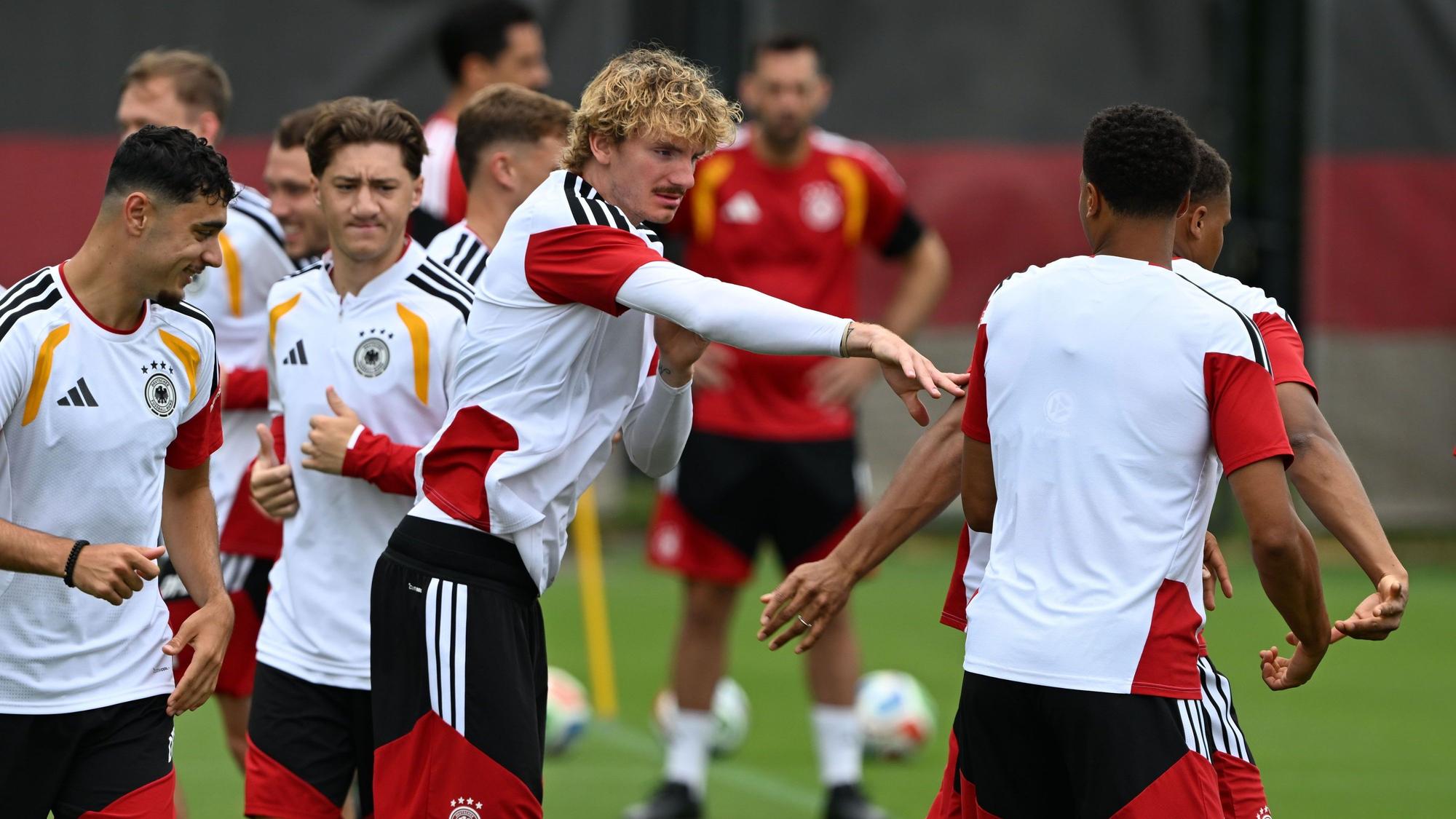 Nick Woltemade (M,l) tippt seinen Mitspieler während des Trainings an.