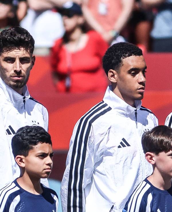 Florian Wirtz, Kai Havertz und Jamal Musiala stehen vor einem Spiel während der Hymne nebeneinander.