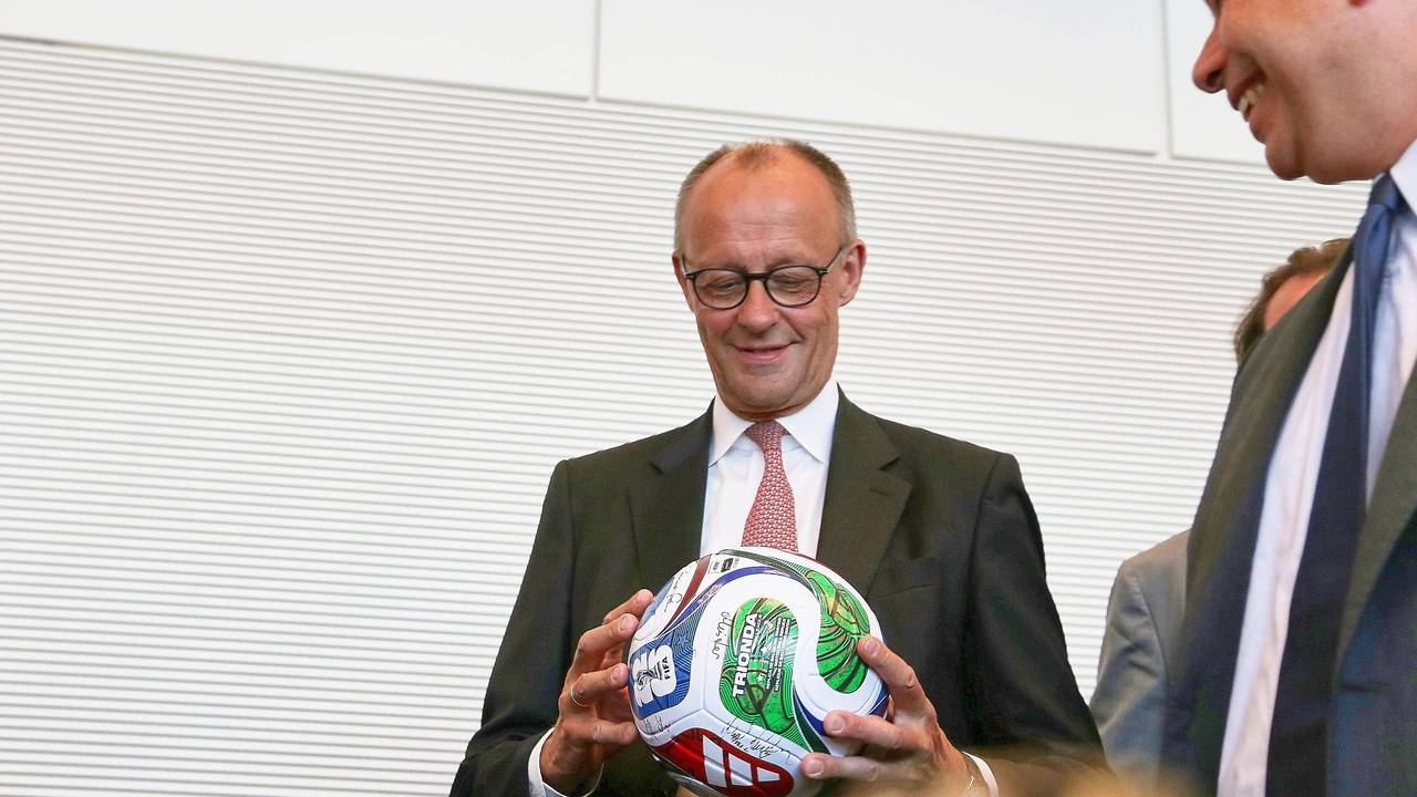 Bundeskanzler Friedrich Merz hält einen Fußball in der Hand.