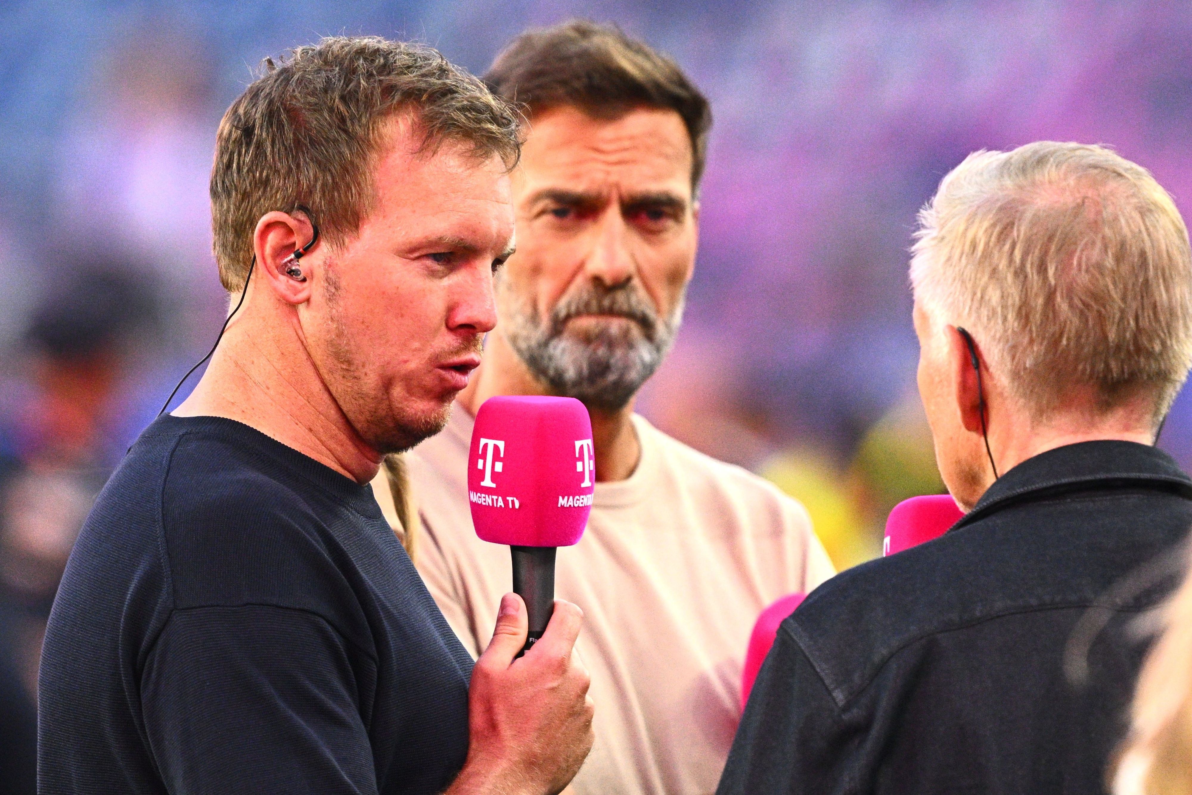 Julian Nagelsmann gibt bei MagentaTV ein Interview, Jürgen Klopp hört ihm zu.
