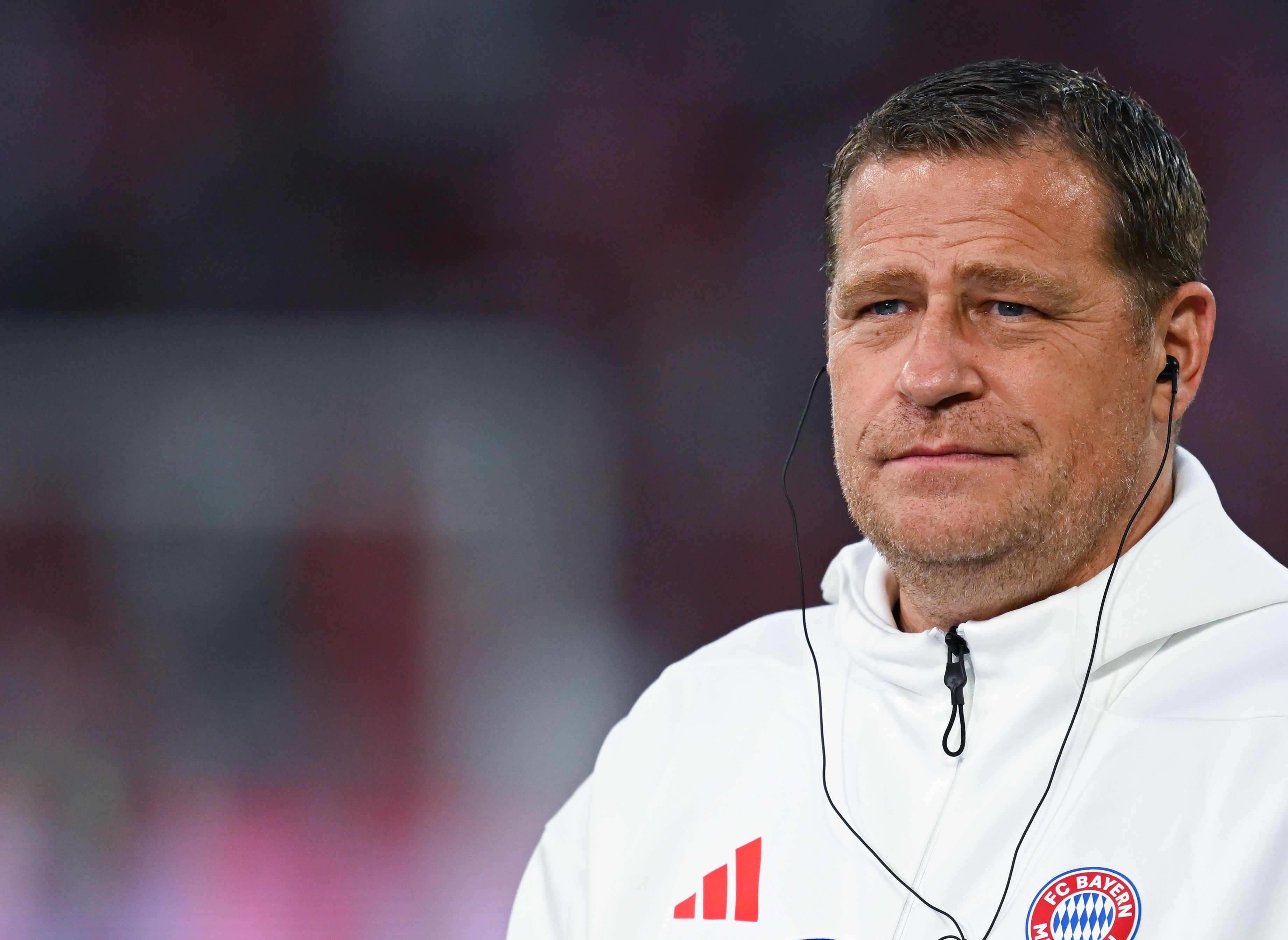 Max Eberl trägt bei einem Interview Kopfhörer im Ohr.