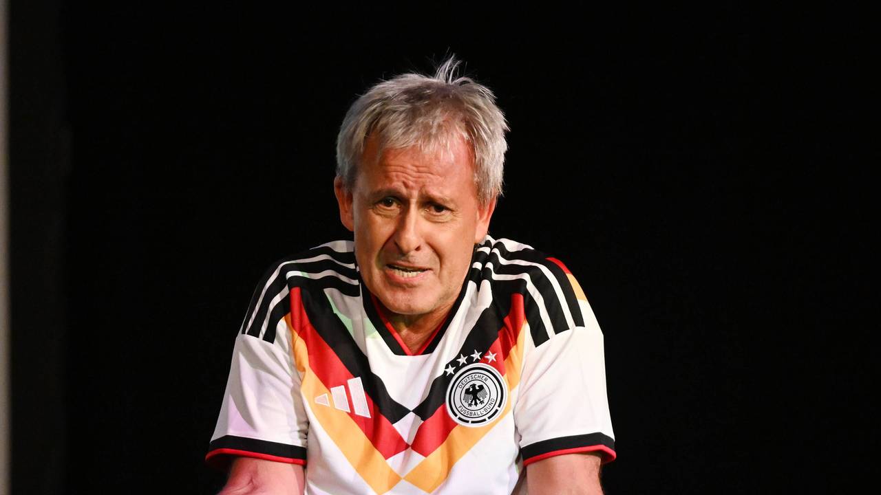 Pierre Littbarski mit Deutschland-Trikot und Mikrofon in der Hand auf der Bühne.