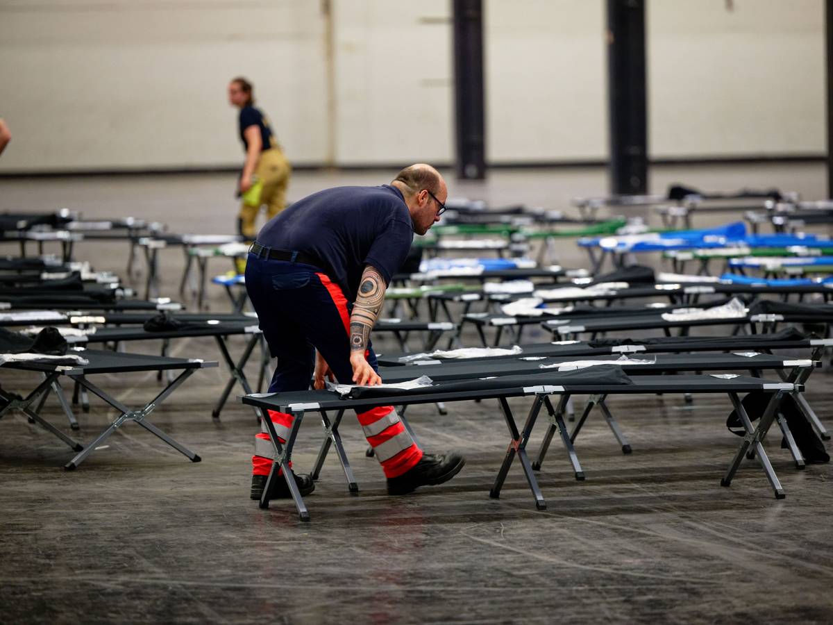 Kräfte des Malteser-Hilfsdienstes bauen Ende Juni im Notfallversorgungszentrum der Feuerwehr Köln in einer gekühlten Messehalle Feldbetten auf.