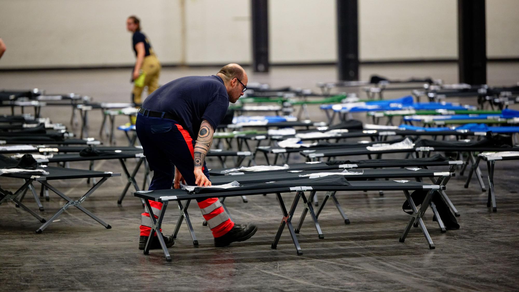 Kräfte des Malteser-Hilfsdienstes bauen Ende Juni im Notfallversorgungszentrum der Feuerwehr Köln in einer gekühlten Messehalle Feldbetten auf.