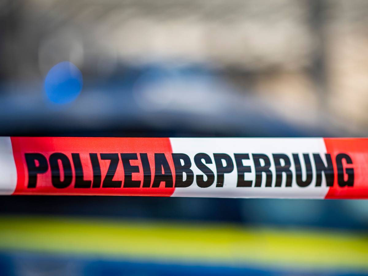 Ein Absperrband mit der Aufschrift „Polizeiabsperrung“ ist vor einem Polizeiwagen aufgespannt. (Symbolfoto)