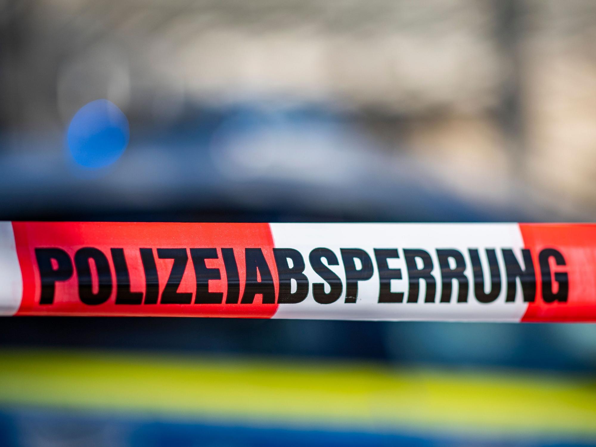 Ein Absperrband mit der Aufschrift „Polizeiabsperrung“ ist vor einem Polizeiwagen aufgespannt. (Symbolfoto)