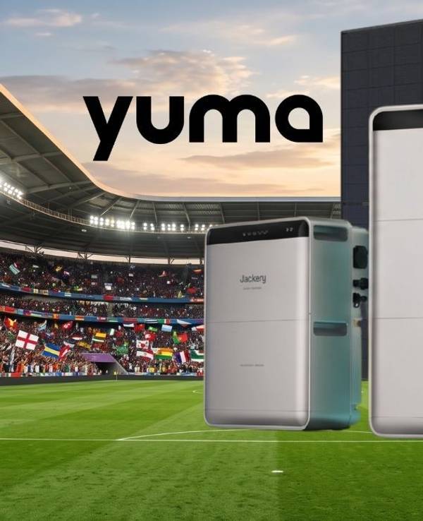 Drei Heimspeicher-Geräte von Anker Solix, EcoFlow und Jackery vor zwei schwarzen Solarmodulen vor einem vollbesetzten Fußballstadion mit Zuschauern und vielen internationalen Flaggen im Hintergrund.