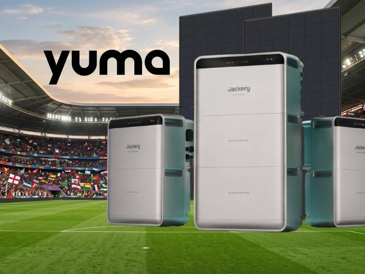 Drei Heimspeicher-Geräte von Anker Solix, EcoFlow und Jackery vor zwei schwarzen Solarmodulen vor einem vollbesetzten Fußballstadion mit Zuschauern und vielen internationalen Flaggen im Hintergrund.