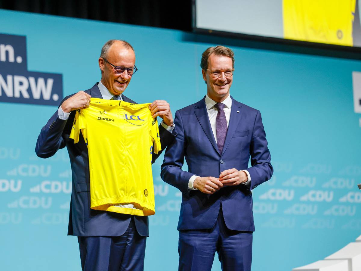 Hendrik Wüst (r., CDU), Ministerpräsident von Nordrhein-Westfalen, überreichte Bundeskanzler Friedrich Merz (CDU) beim Landesparteitag der CDU Nordrhein-Westfalen ein gelbes Rennradtrikot.